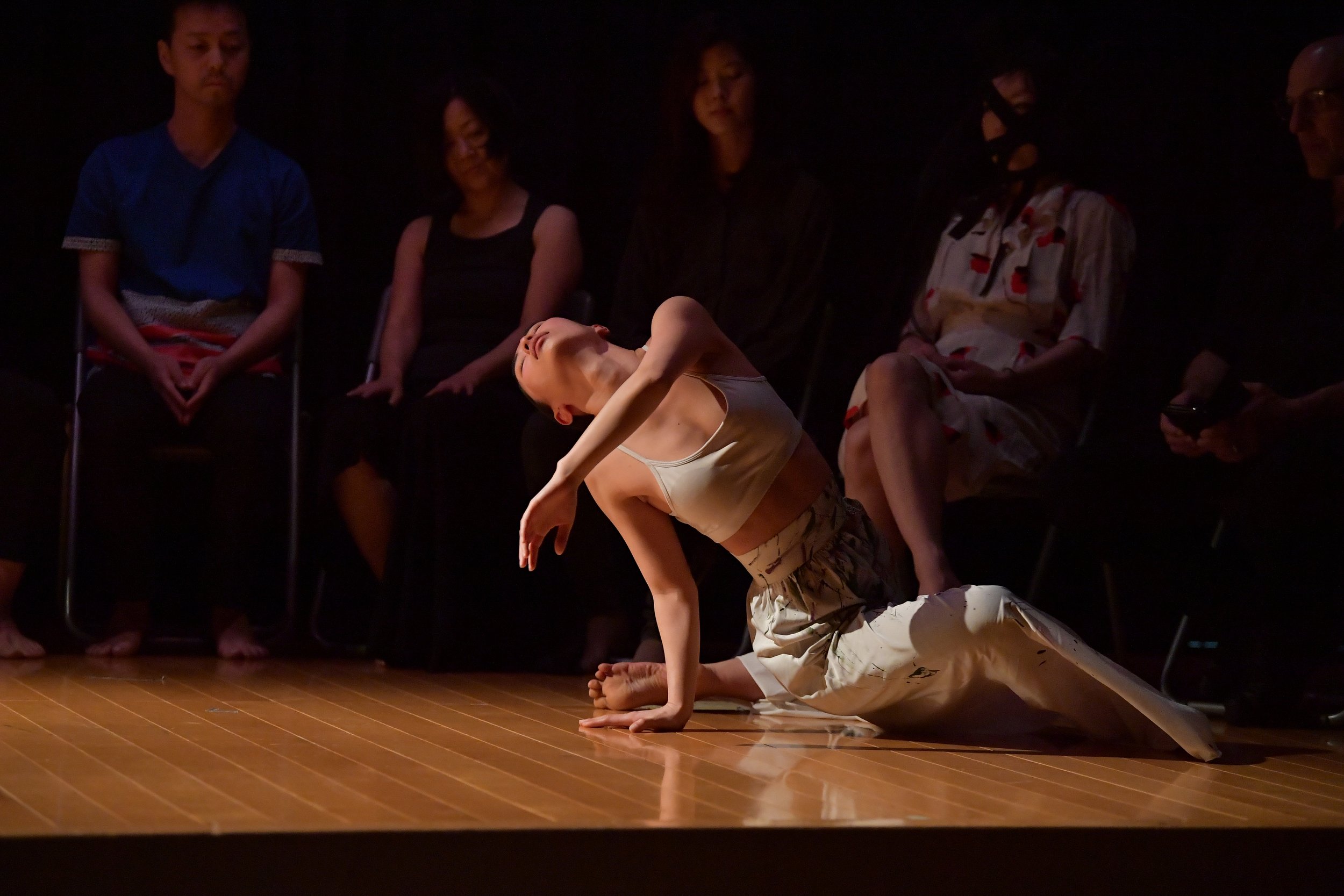 A dancer sits on the floor with one leg in front of them and one behind.