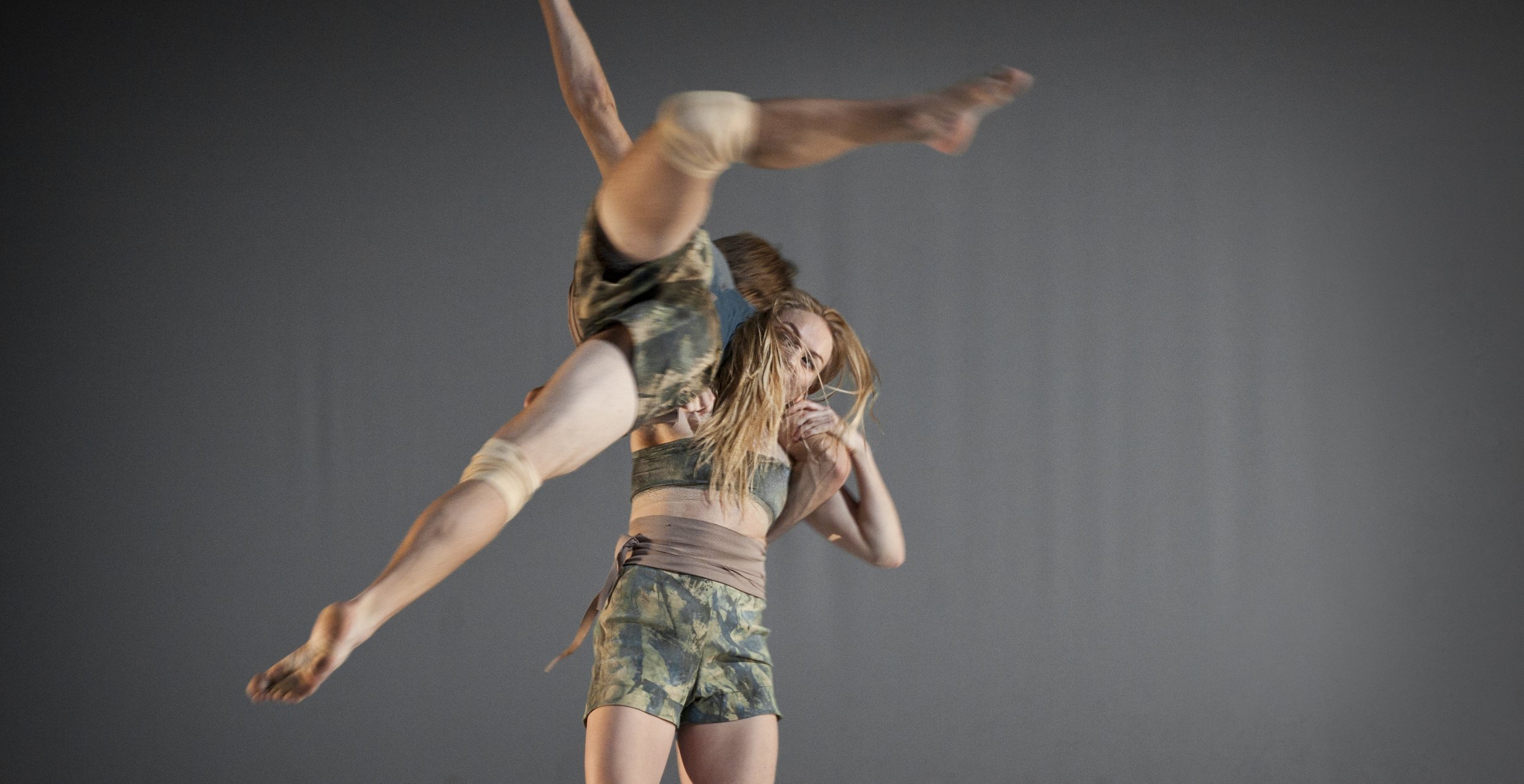 One dancer lifts another dancer over their shoulder.