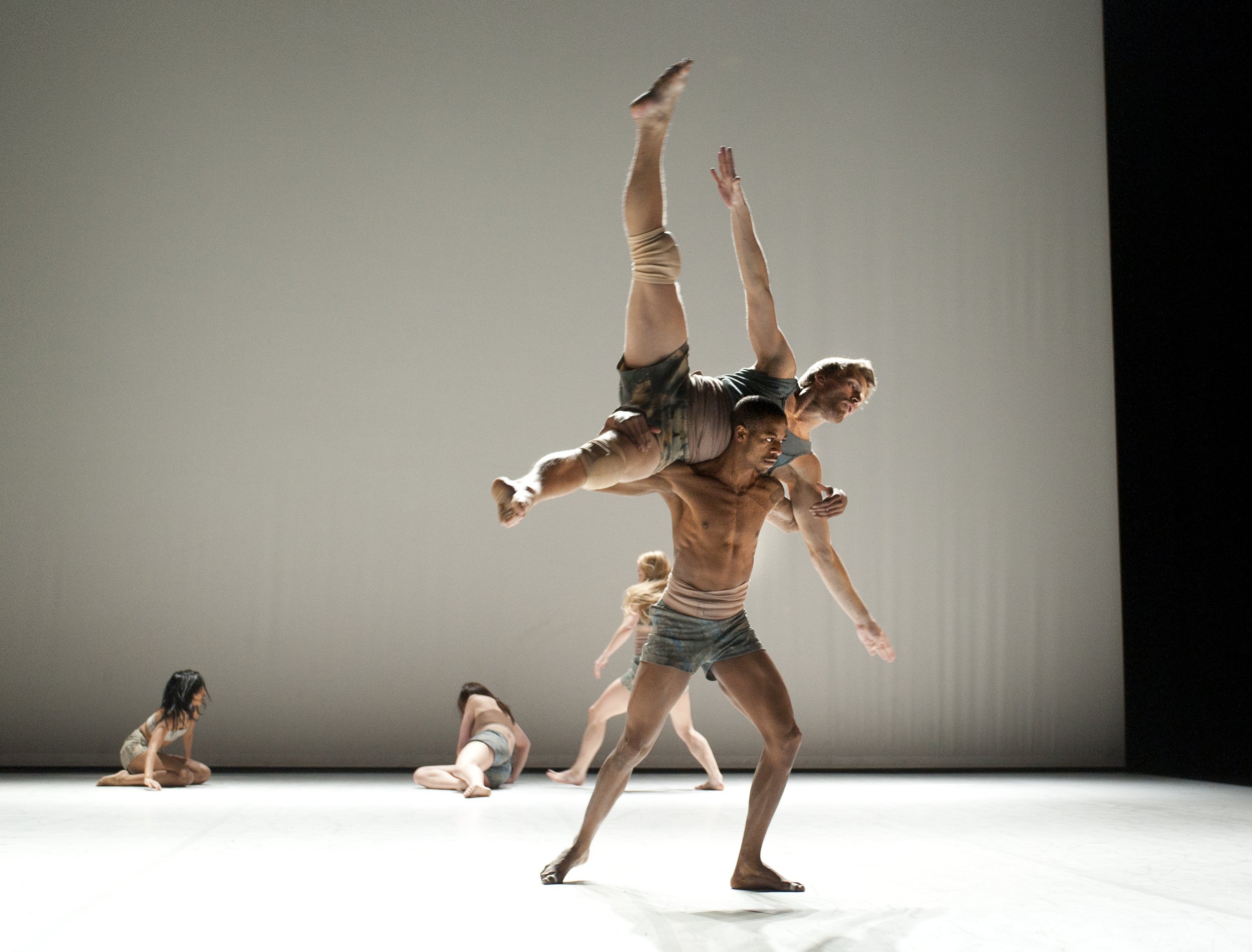 One dancer carries another dancer across both their shoulders.