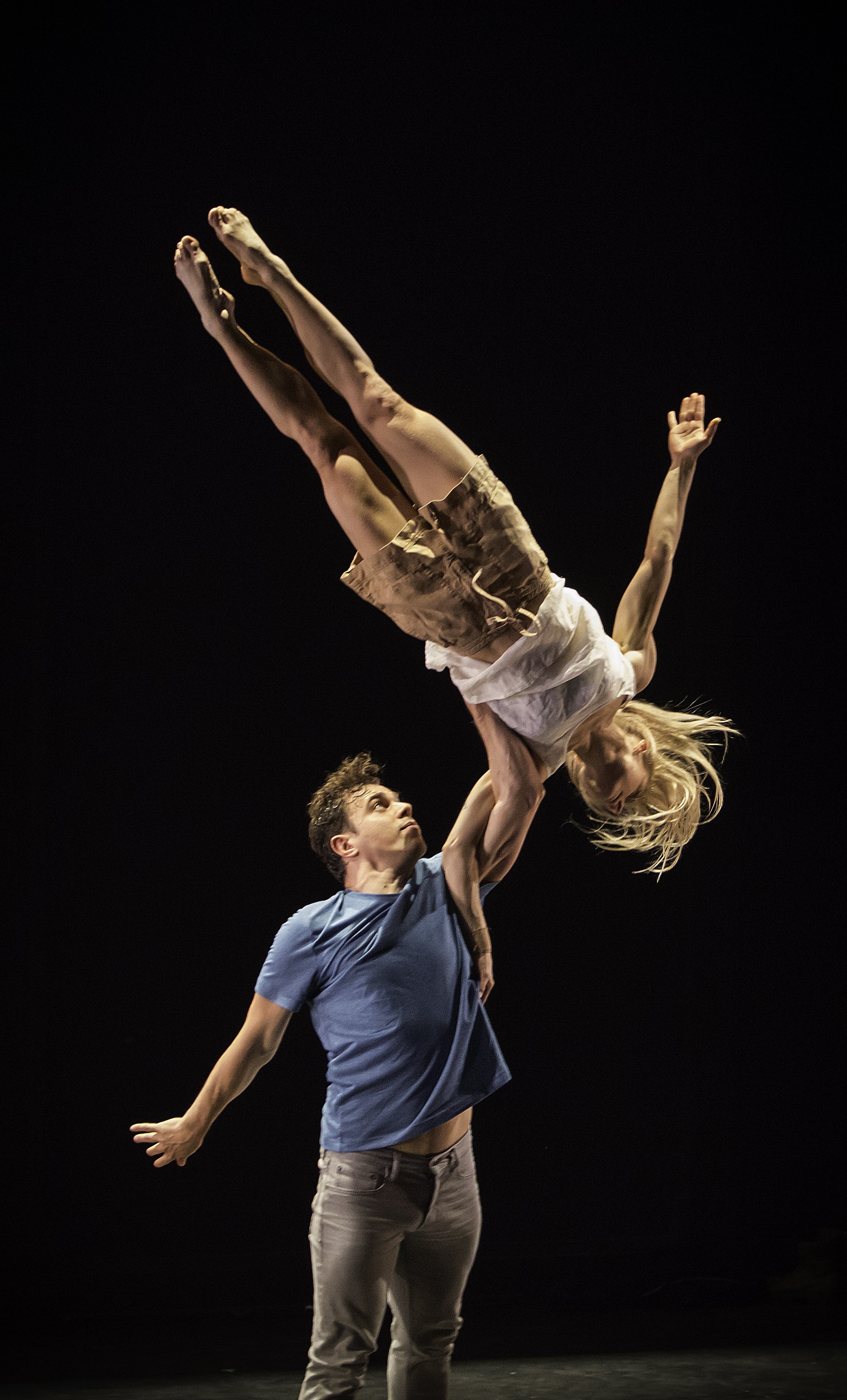 One dancer lifts another above their head.