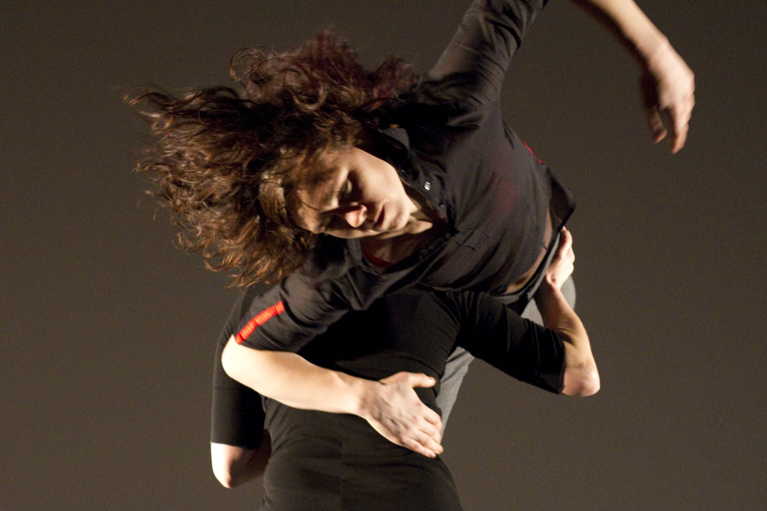 A close up of a dancer being lifted over the shoulder of another dancer.