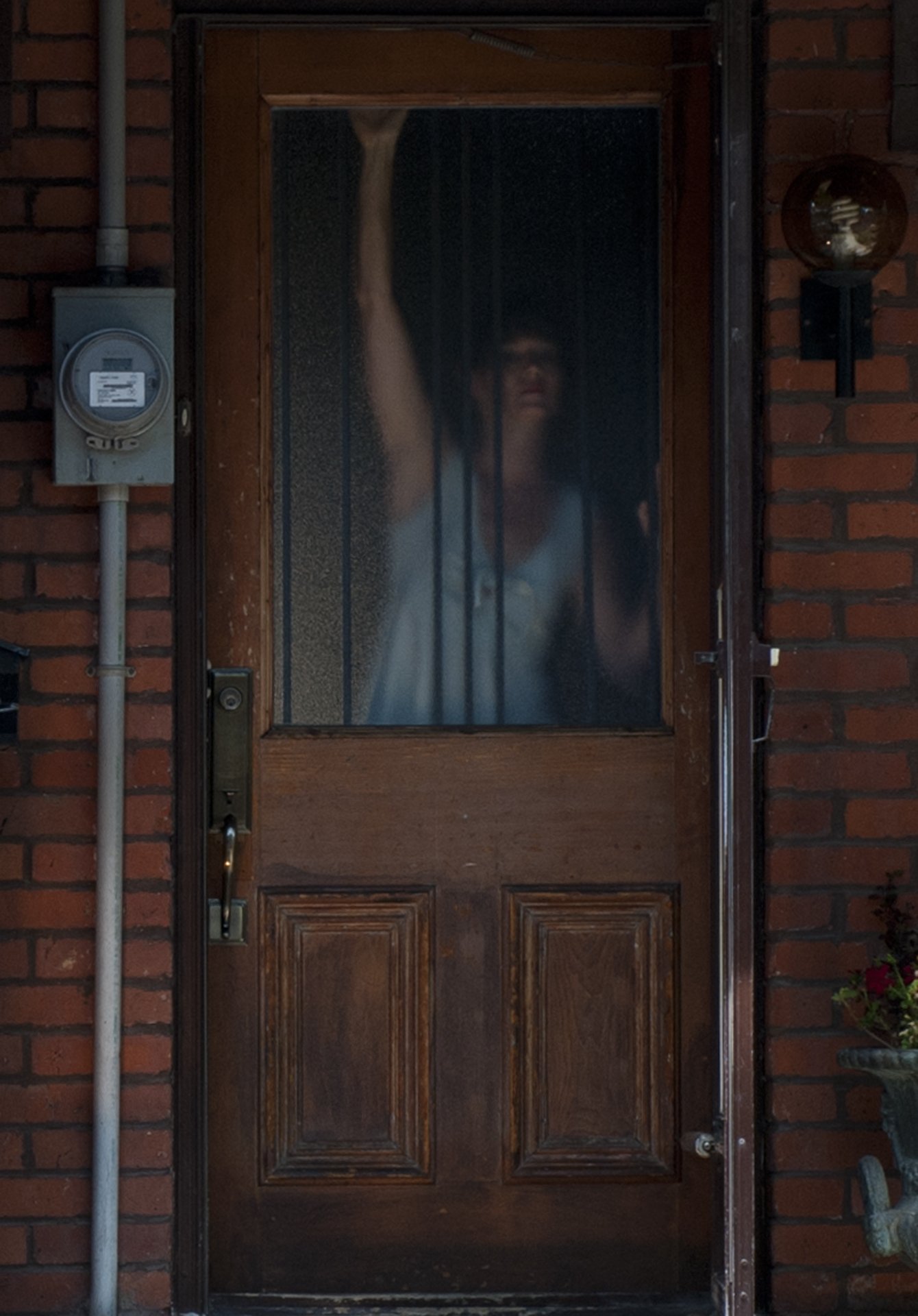 A person seen through the window in a closed front door.
