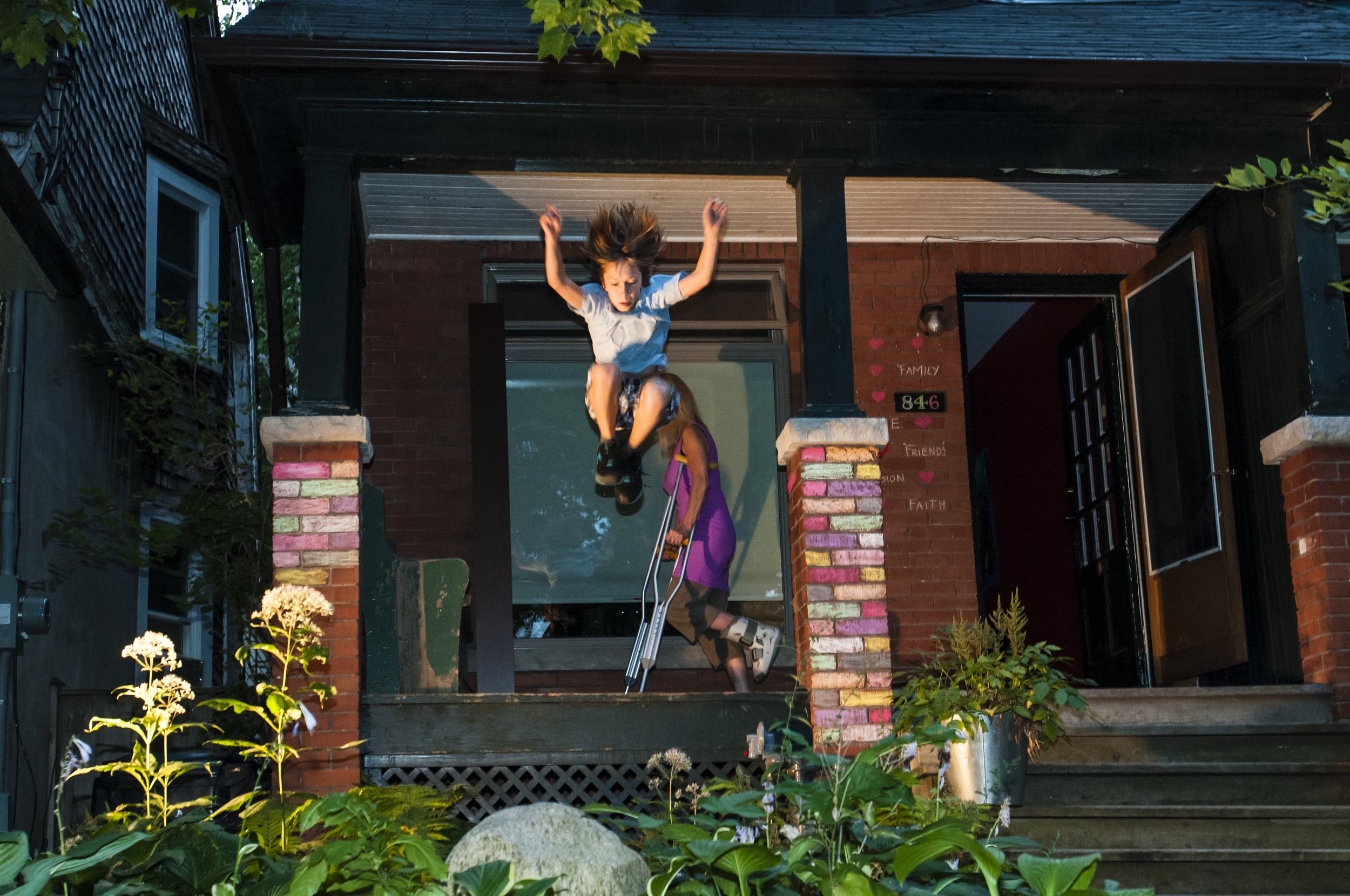 A child in mid-air jumping off of a porch.