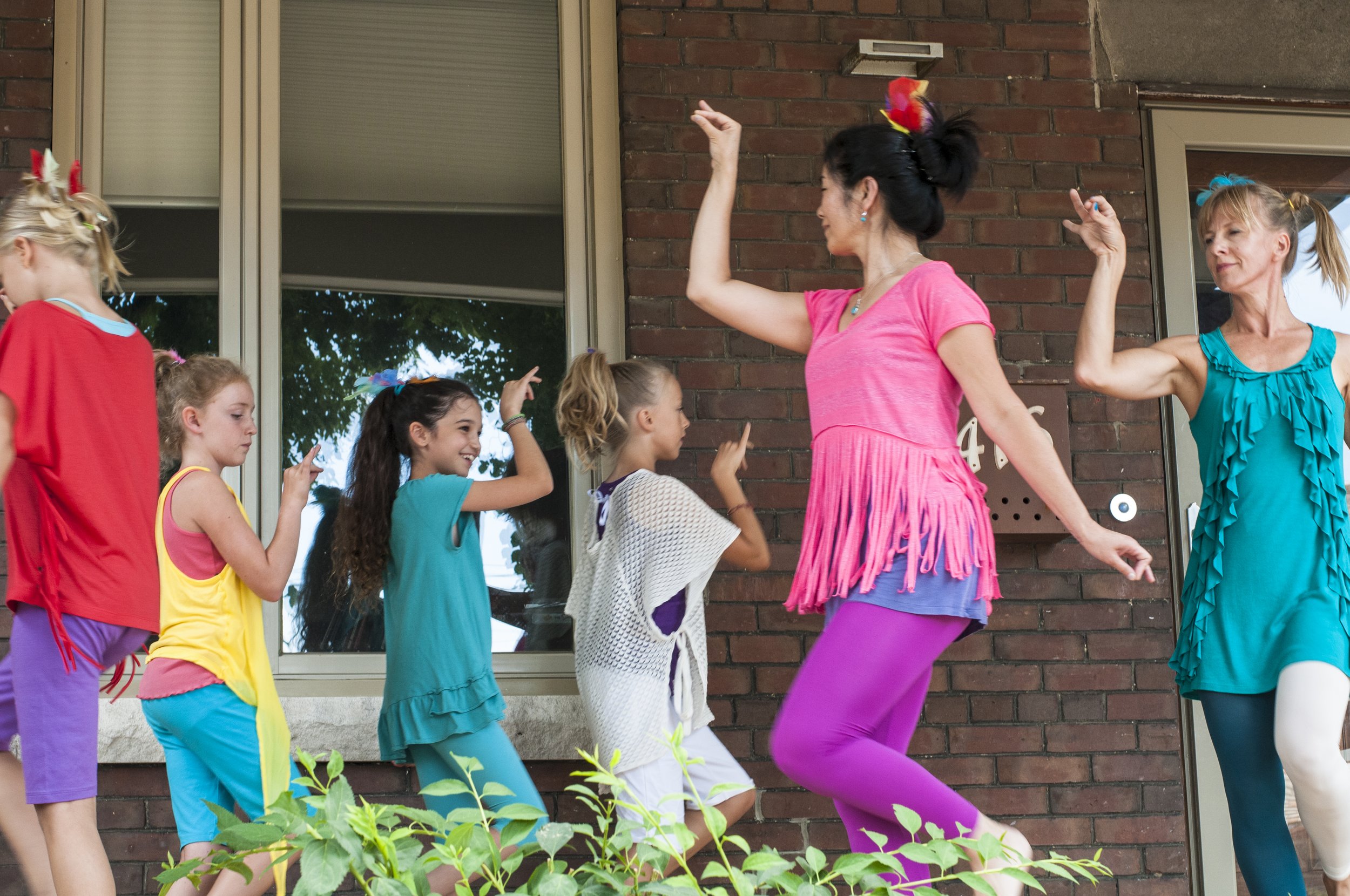 A group of young community participants dancing on a porch.