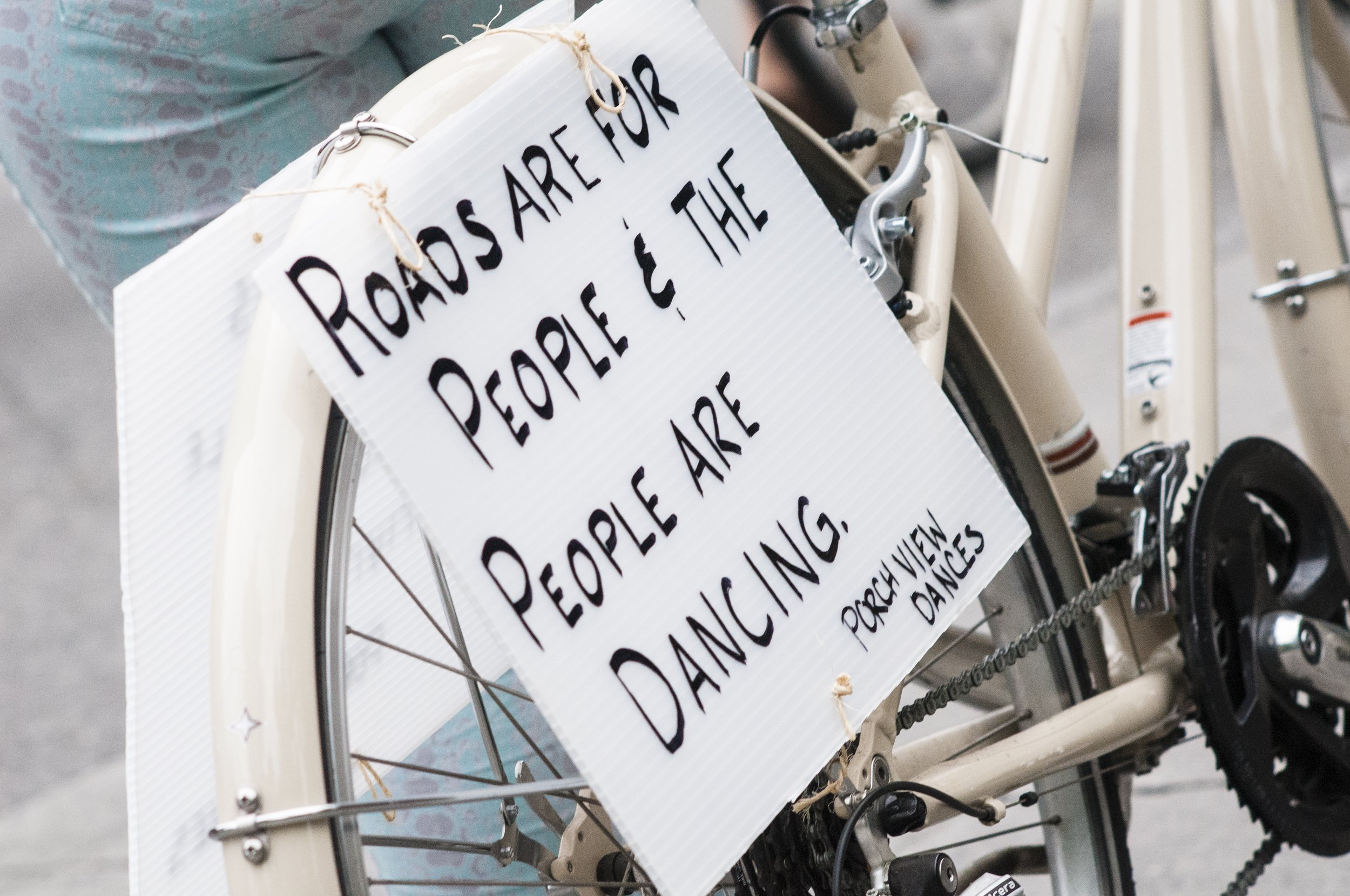 A sign on a bike tire: "Rpads are for people &amp; the people are dancing. Porch View Dances"