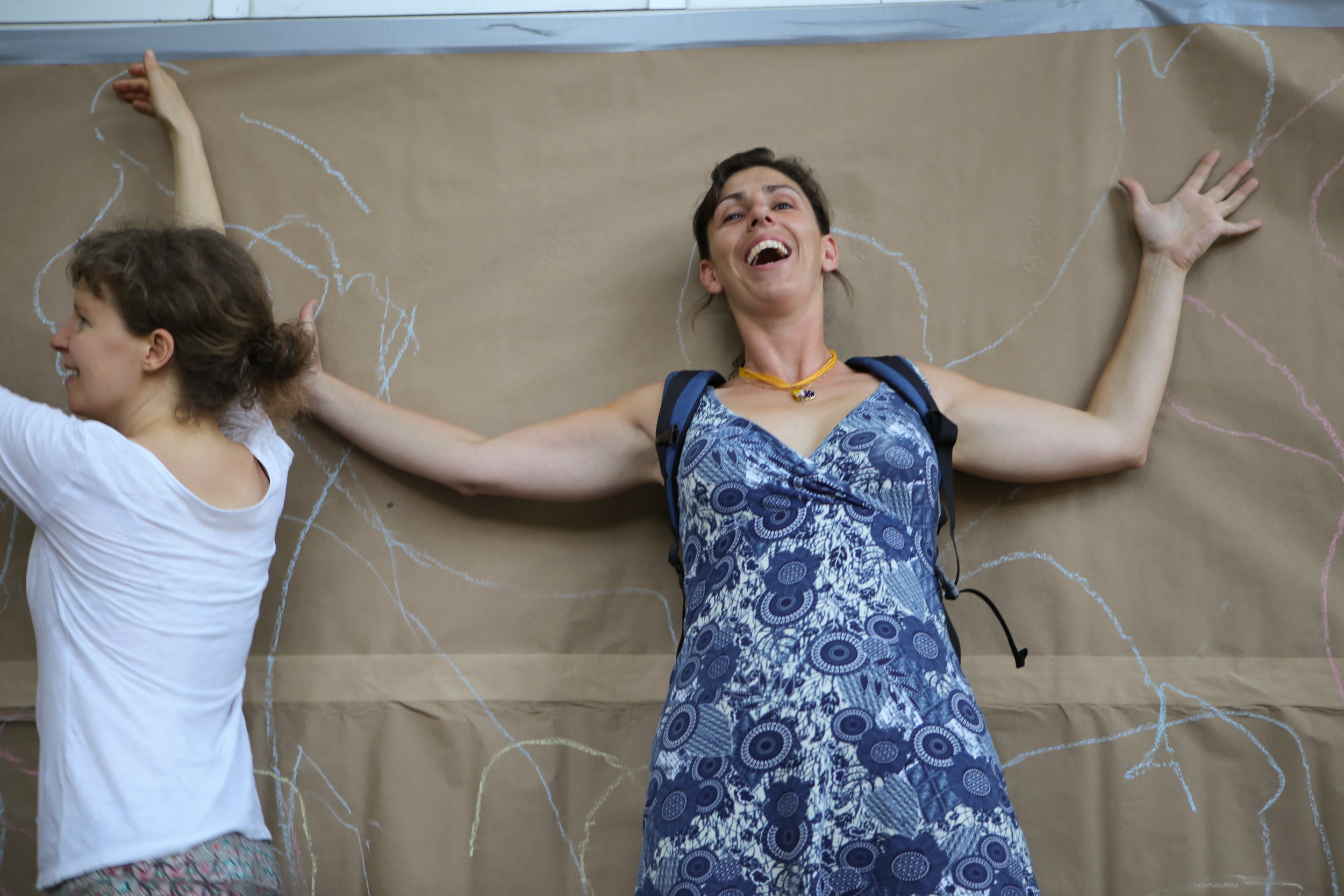 Woman laughing against a wall, with chalk tracings of body poses behind her