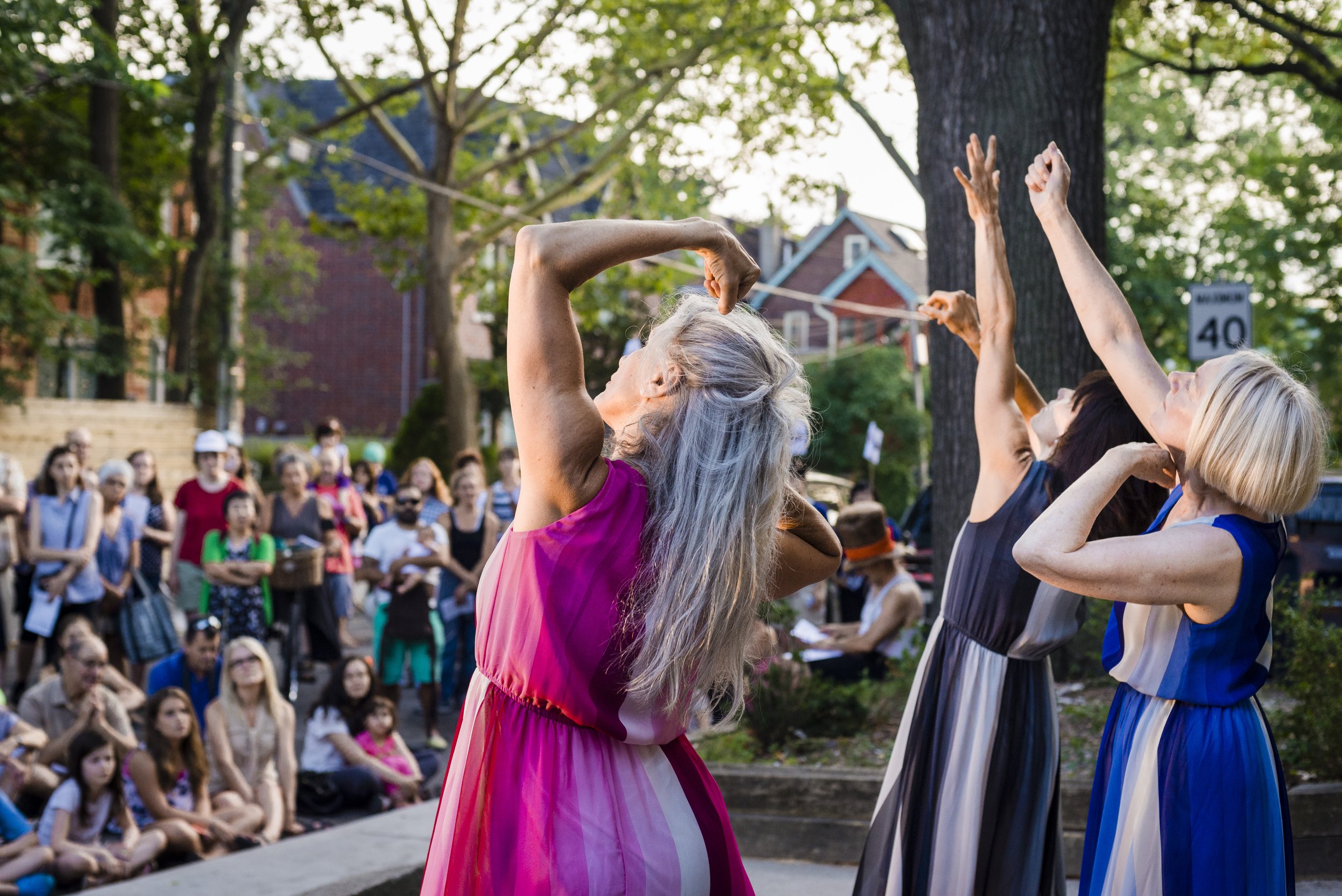 Trio of women, each reaching for the sky in front of a engaged audience