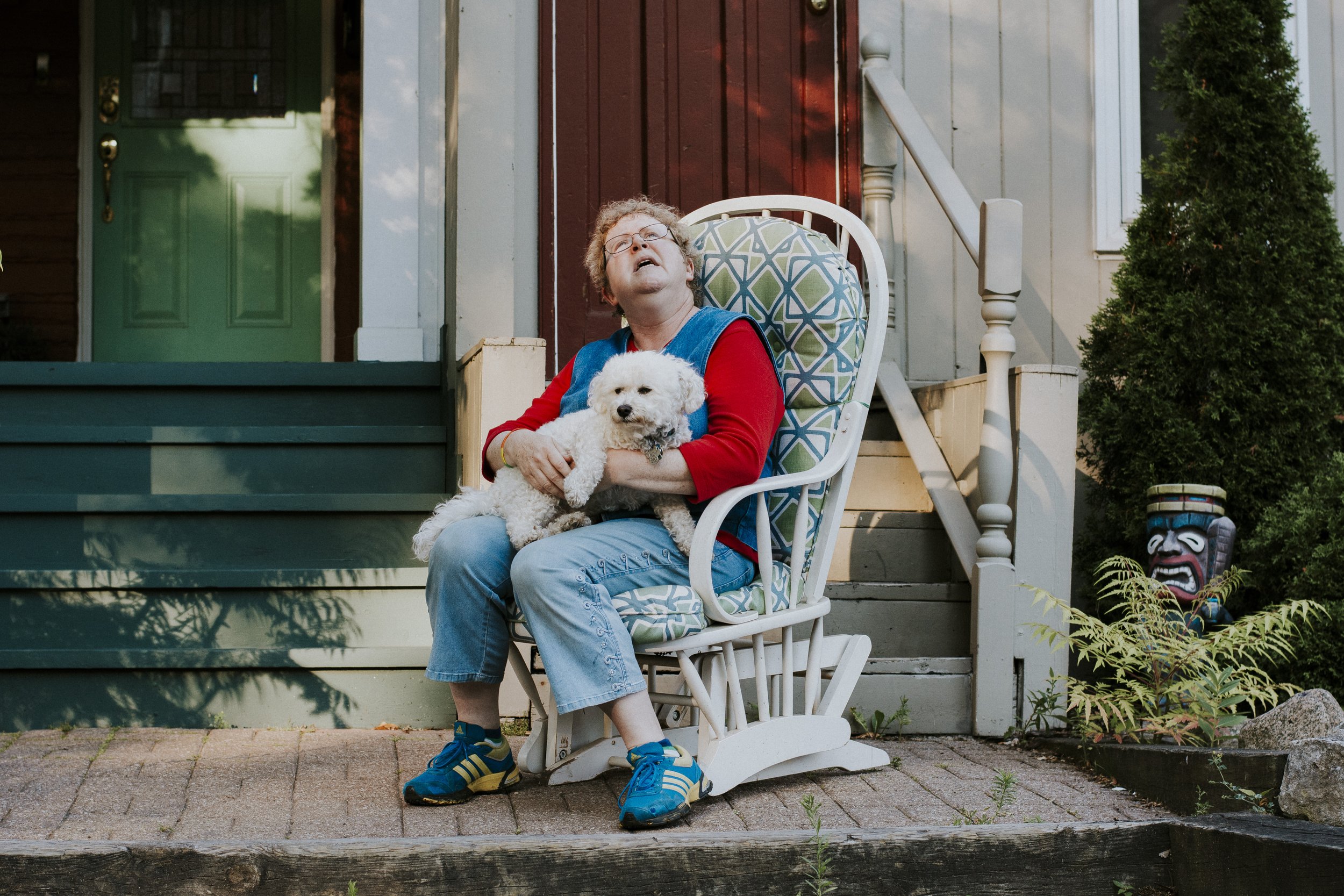 Sitting peacefully with a dog in their lap on a rocking chair, gazing at the sky