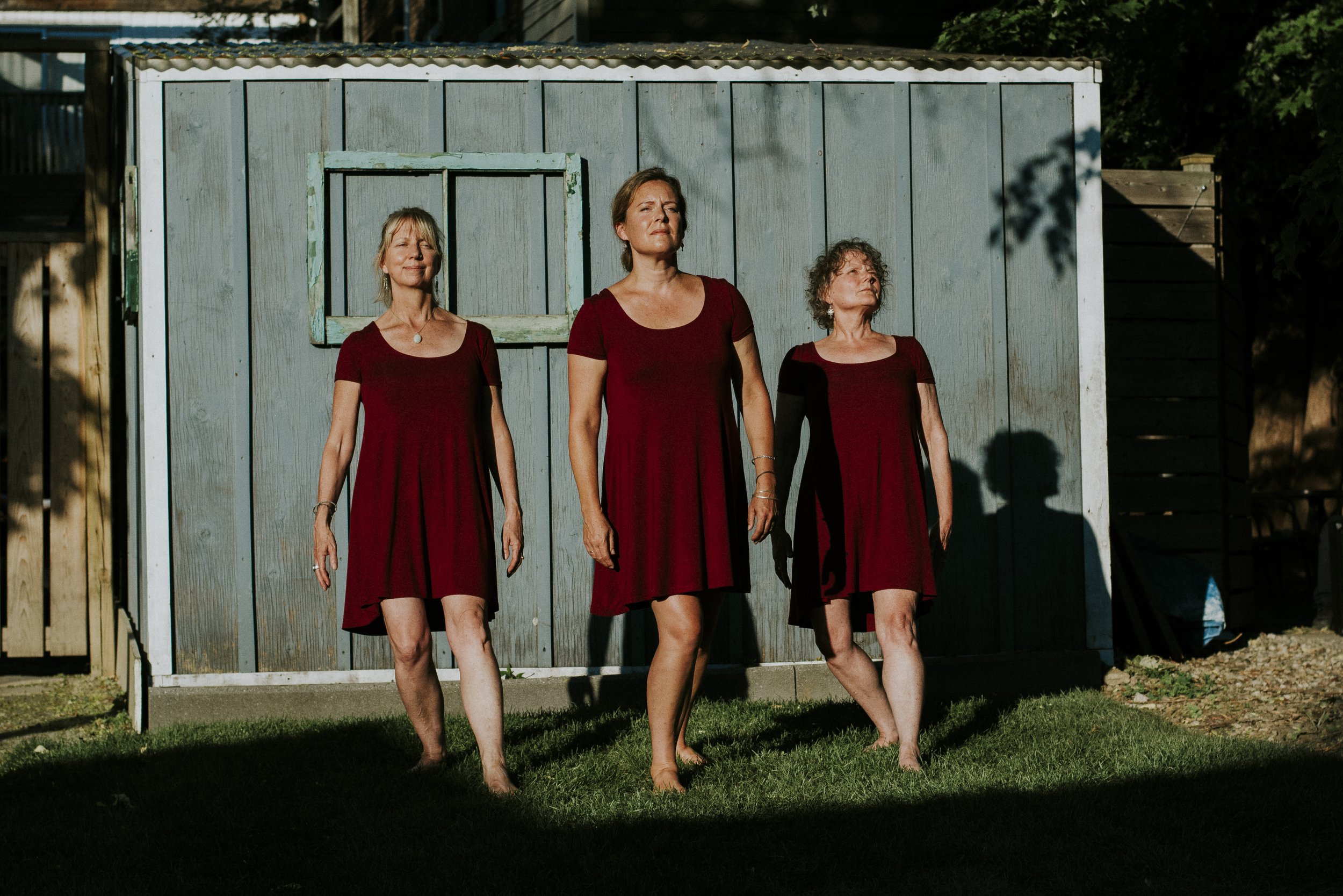 Three women in red dresses, standing proudly, while standing in a strong sunlight