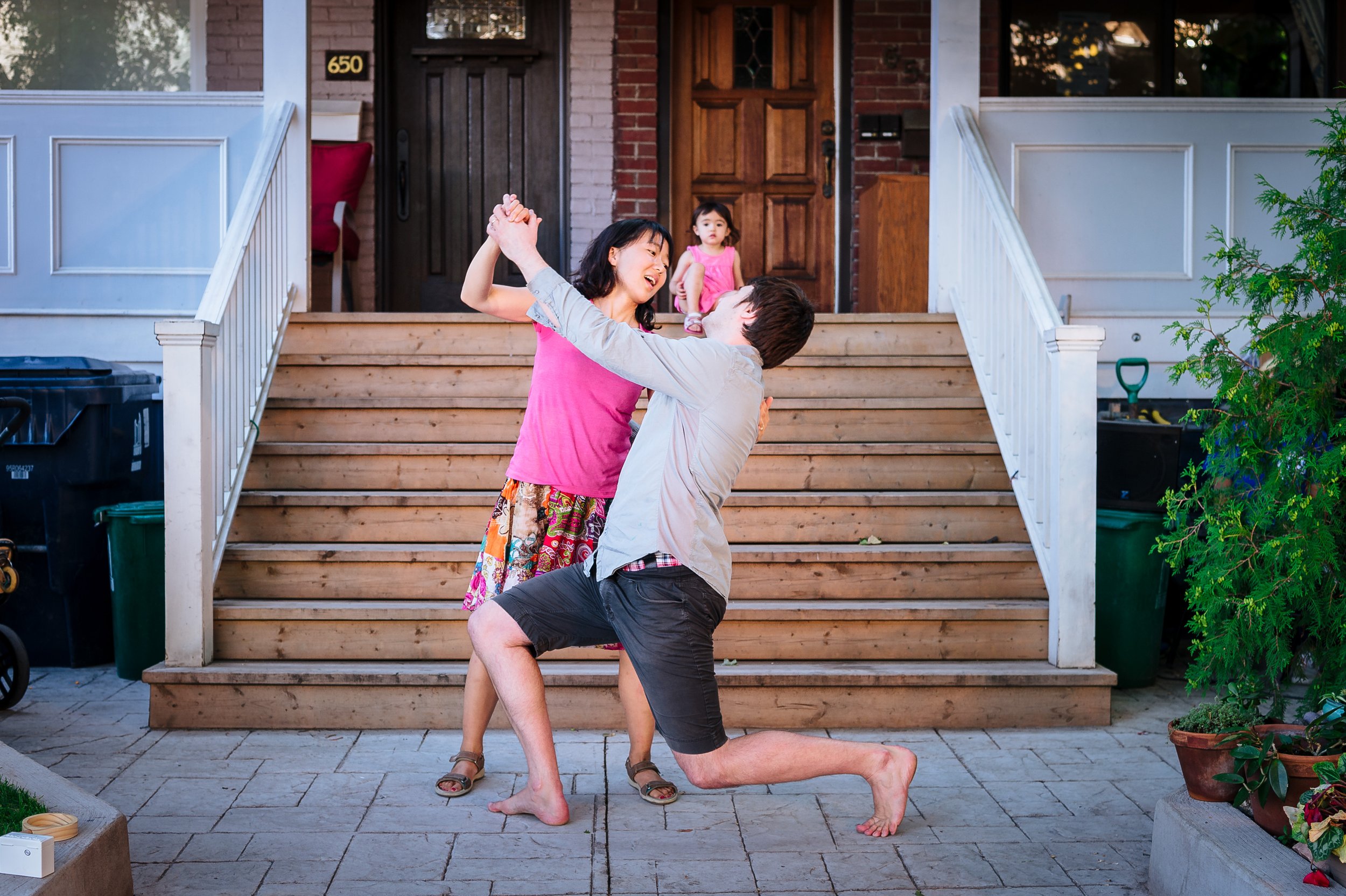 Couple doing the tango in front of daughter who watches from the porch stairs