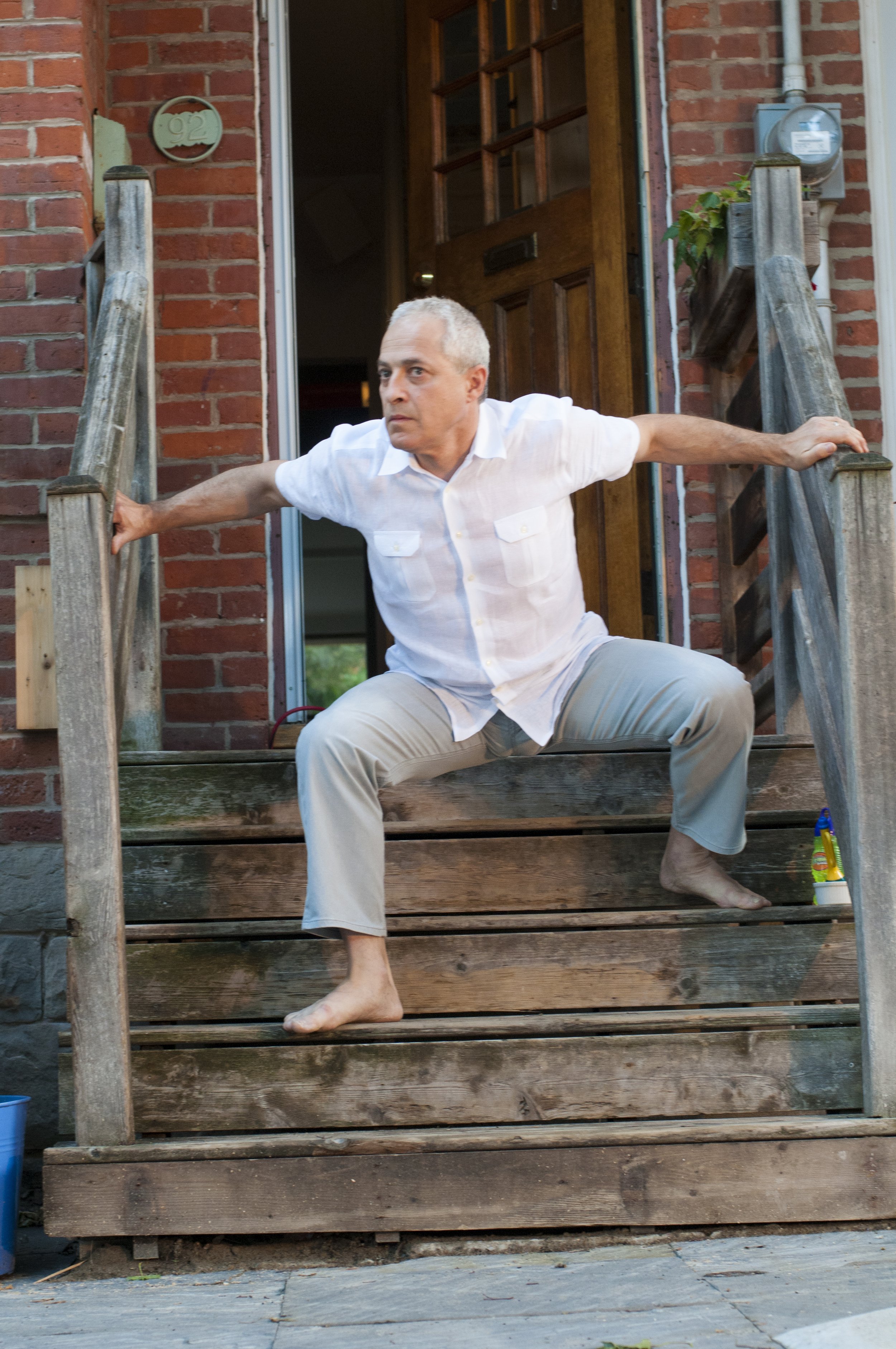 Man descending a wooden porch while in a squat