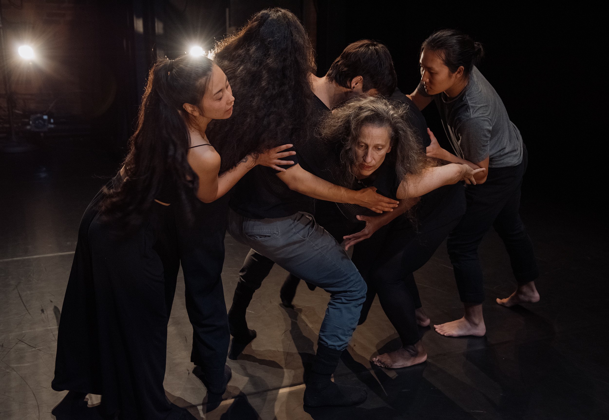  Four performers form a human wall that catches Karen Kaeja, an Ashkenazi white female with long grey hair. 