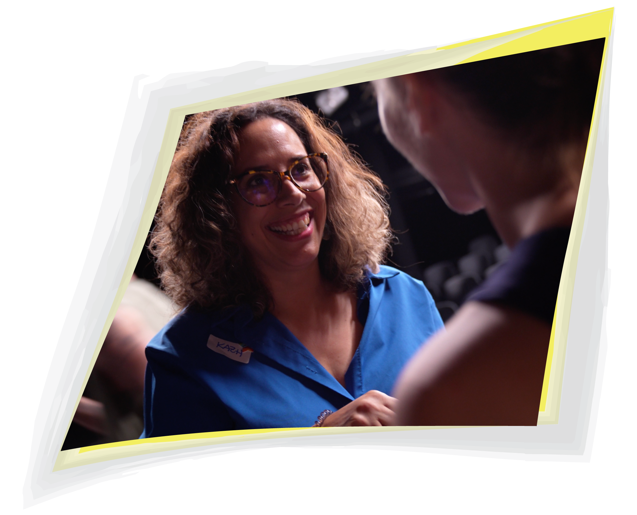 Woman in a blue shirt smiling in conversation with another participant
