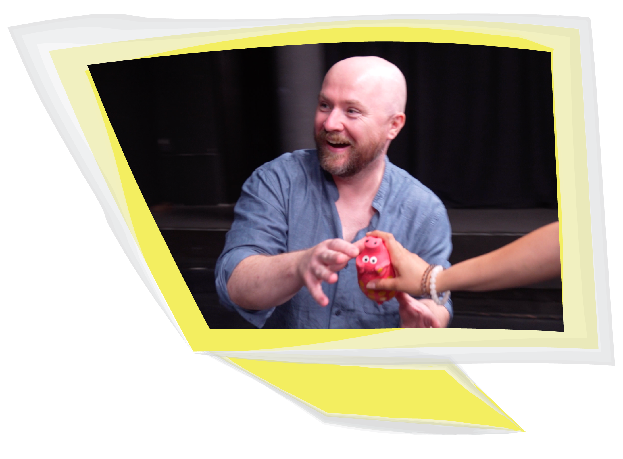 Smiling man passing a small red toy to another person