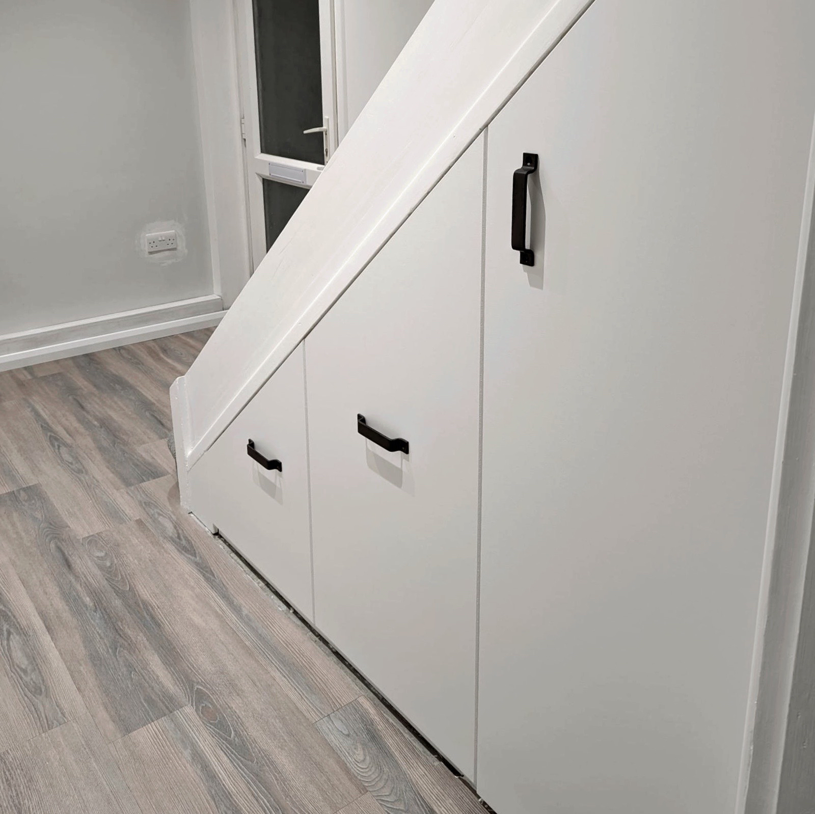 understairs storage with plain doors painted grey with black metal handles