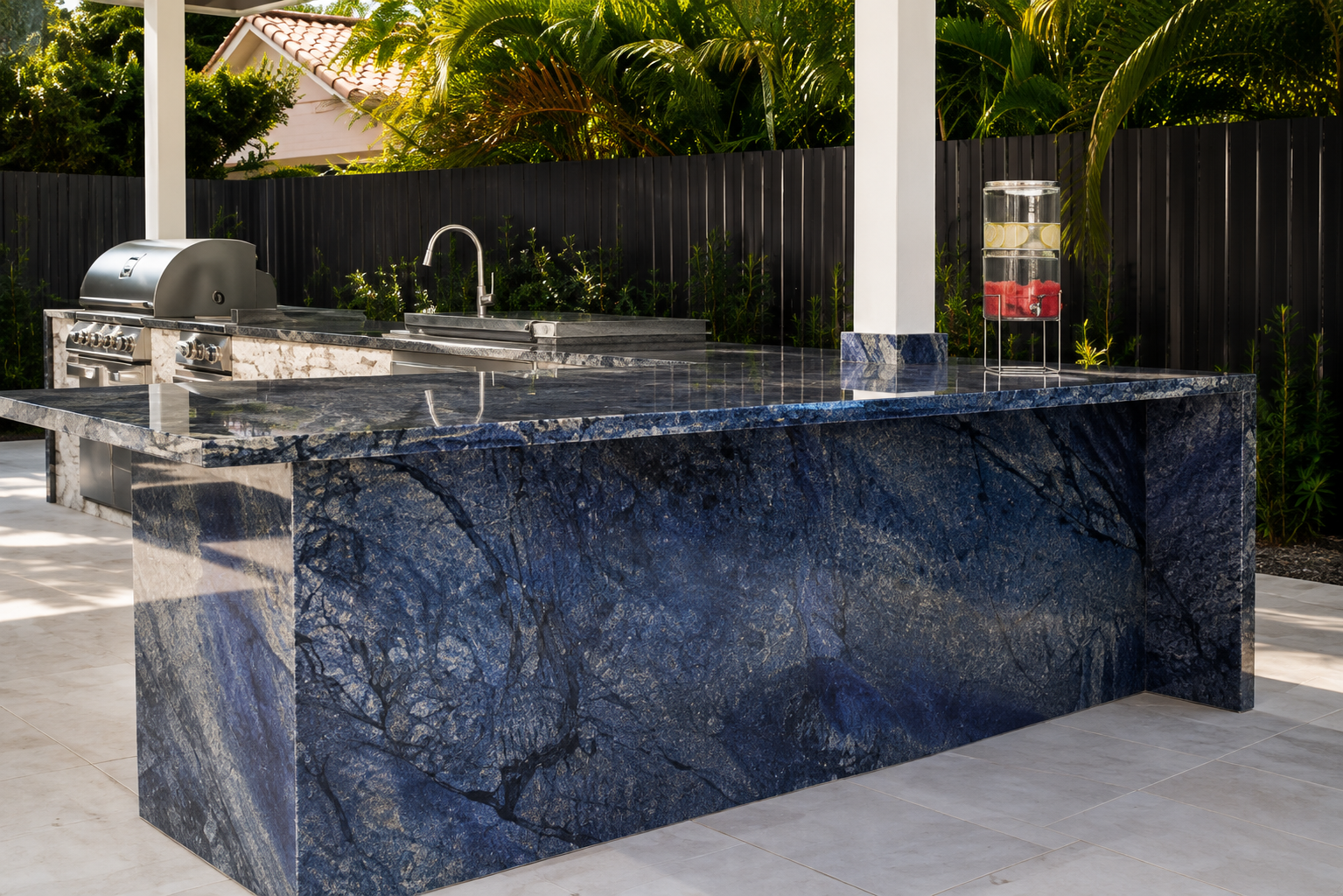 Premium outdoor kitchen featuring dramatic blue granite waterfall countertops, built-in BBQ, sink, and luxury stone surfaces designed for Florida outdoor living.
