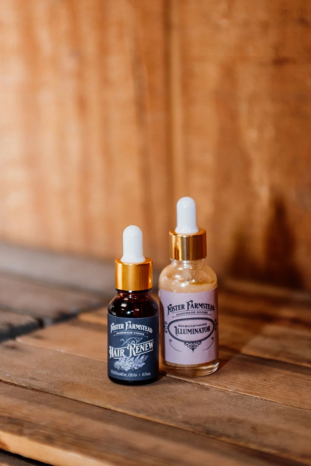 Two small bottles of handmade herbal tinctures with white dropper caps placed on a wooden surface.