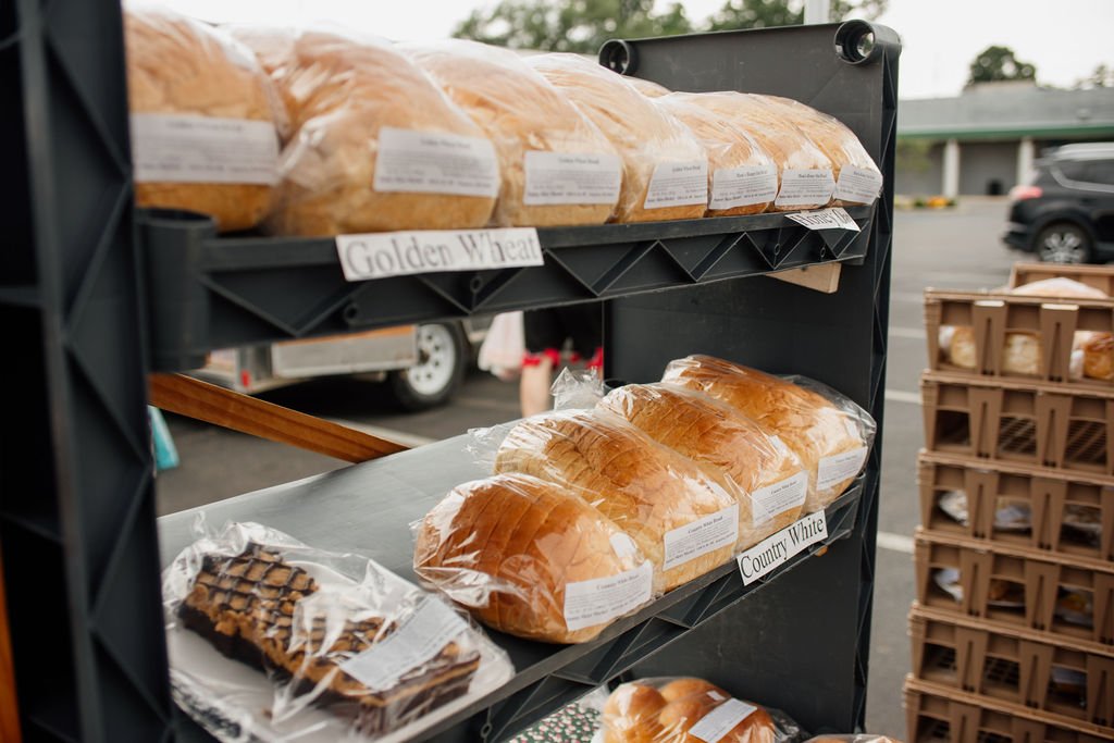 Display of sliced breads on store shelves labeled 'Golden Wheat' and 'Country White' wrapped in plastic.