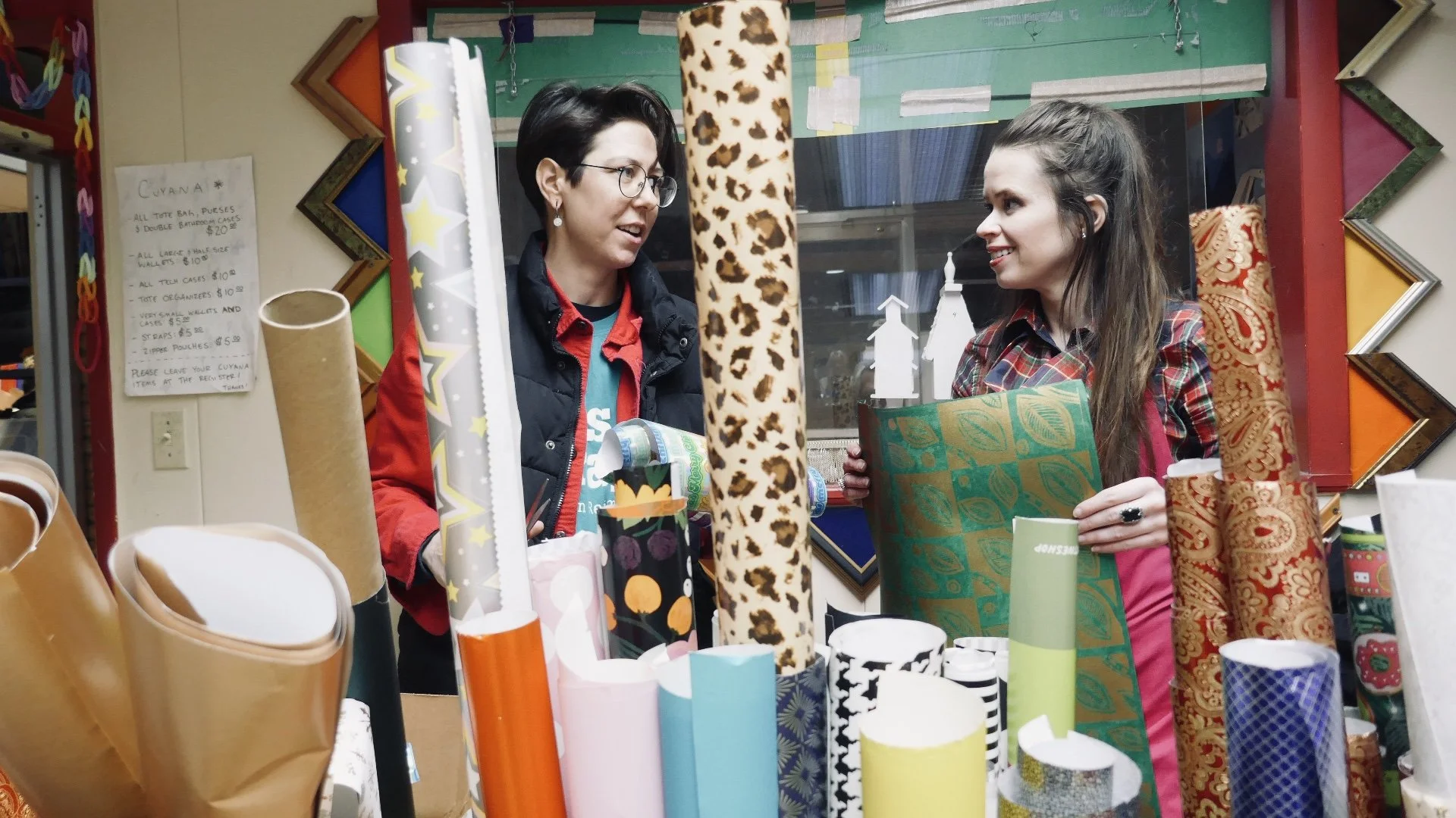 Wrapping paper, pine branches, pinecones, dried orange slices, scissors, and ribbon on a wooden surface, preparing for gift wrapping.