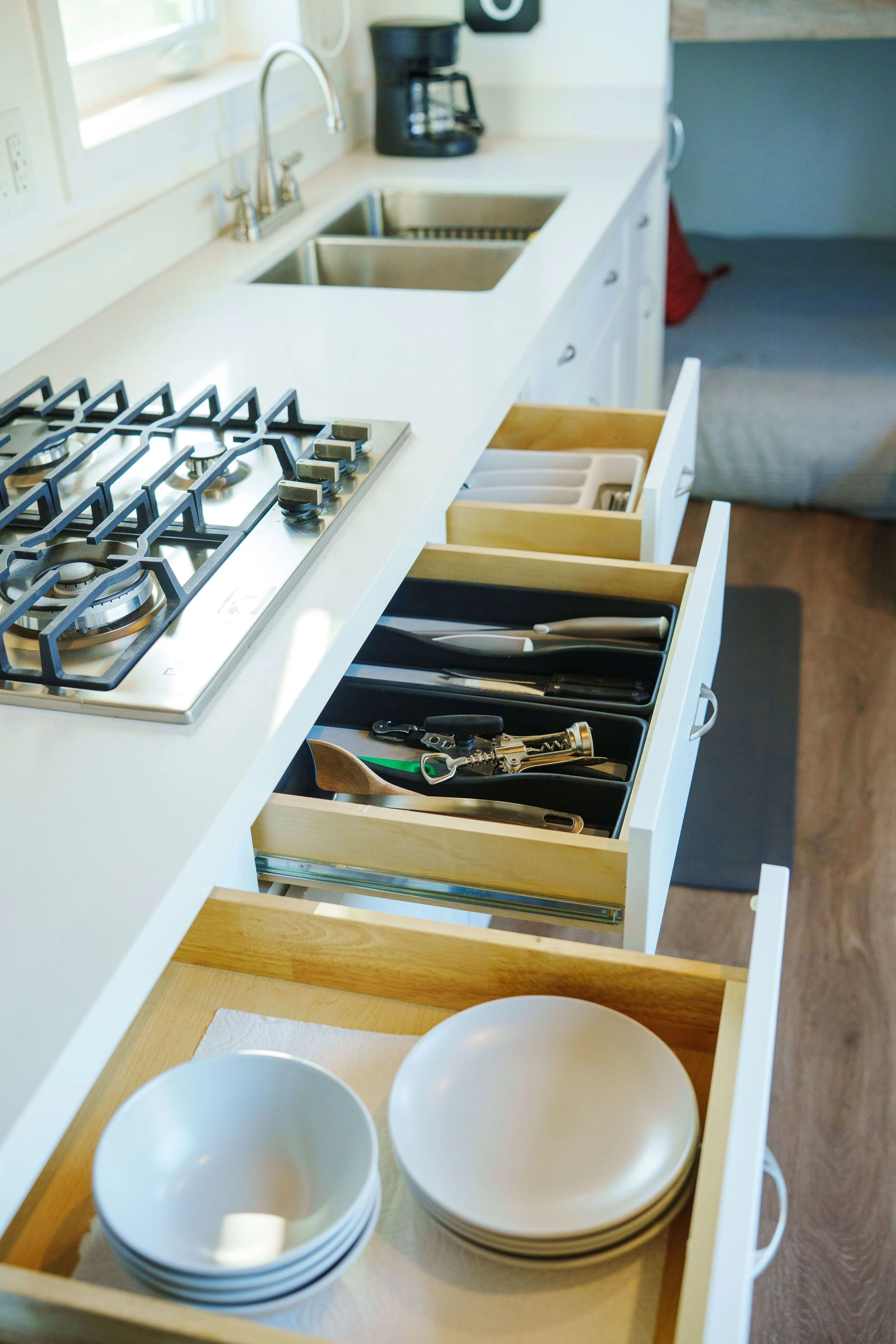 Kitchen drawer with utensils and white bowls inside.