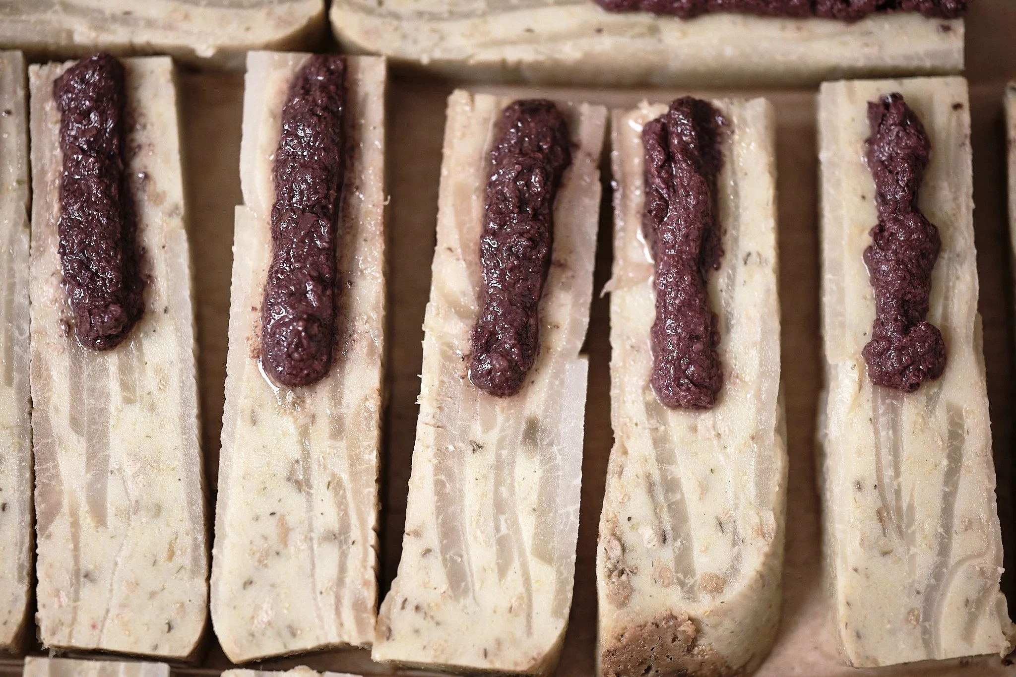 A row of kohlrabi and chopped Kalamata olives. Gauthier Soho, London, England, UK, 2024. Nathalie Merle / We Animals