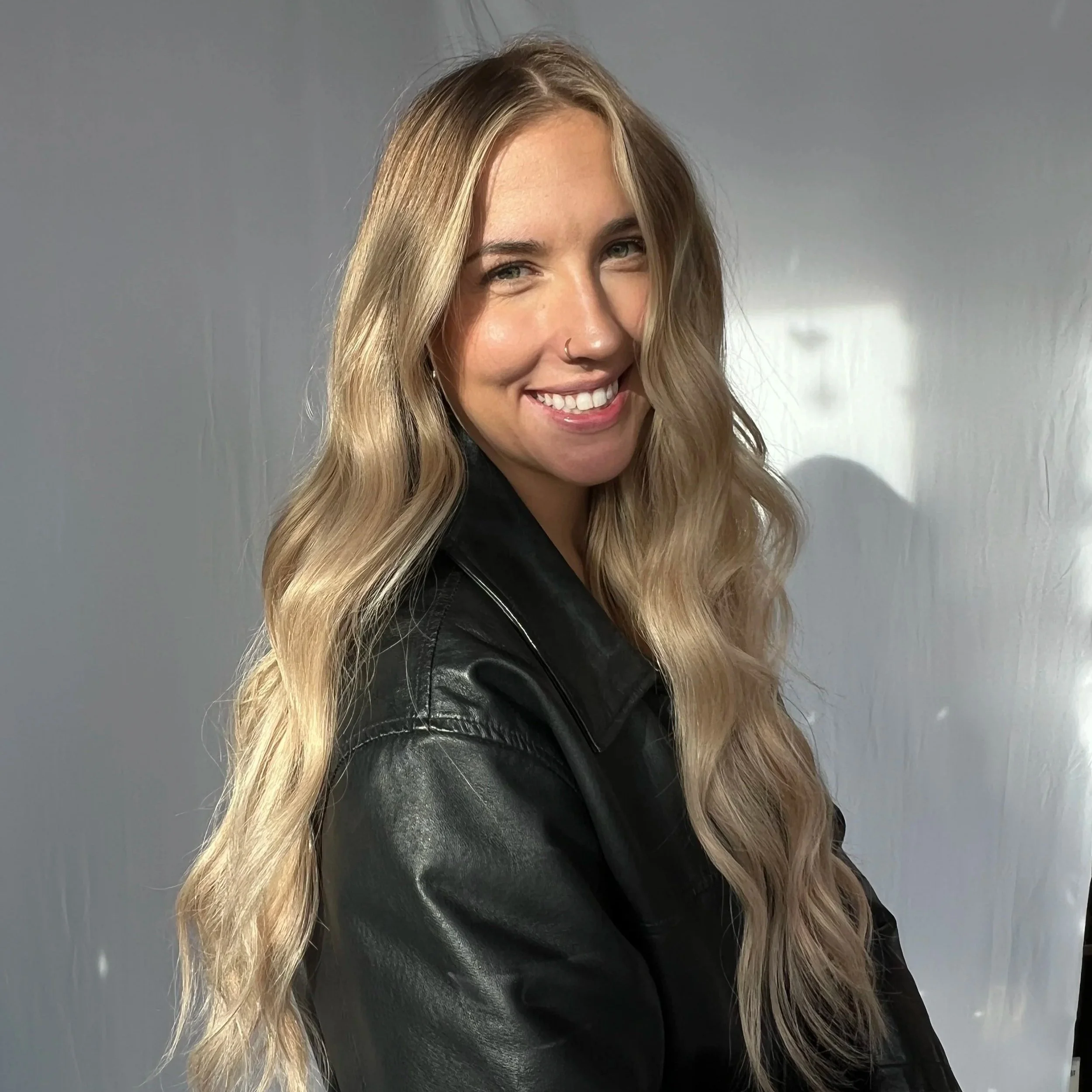 Interior of a hair salon or barbershop with a black chair, a large mirror, and wooden shelves on the wall.
