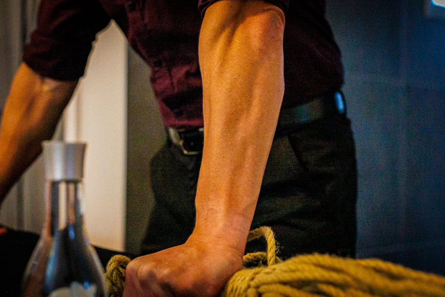 Man in a suit holding a rope beside a massage oil bottle