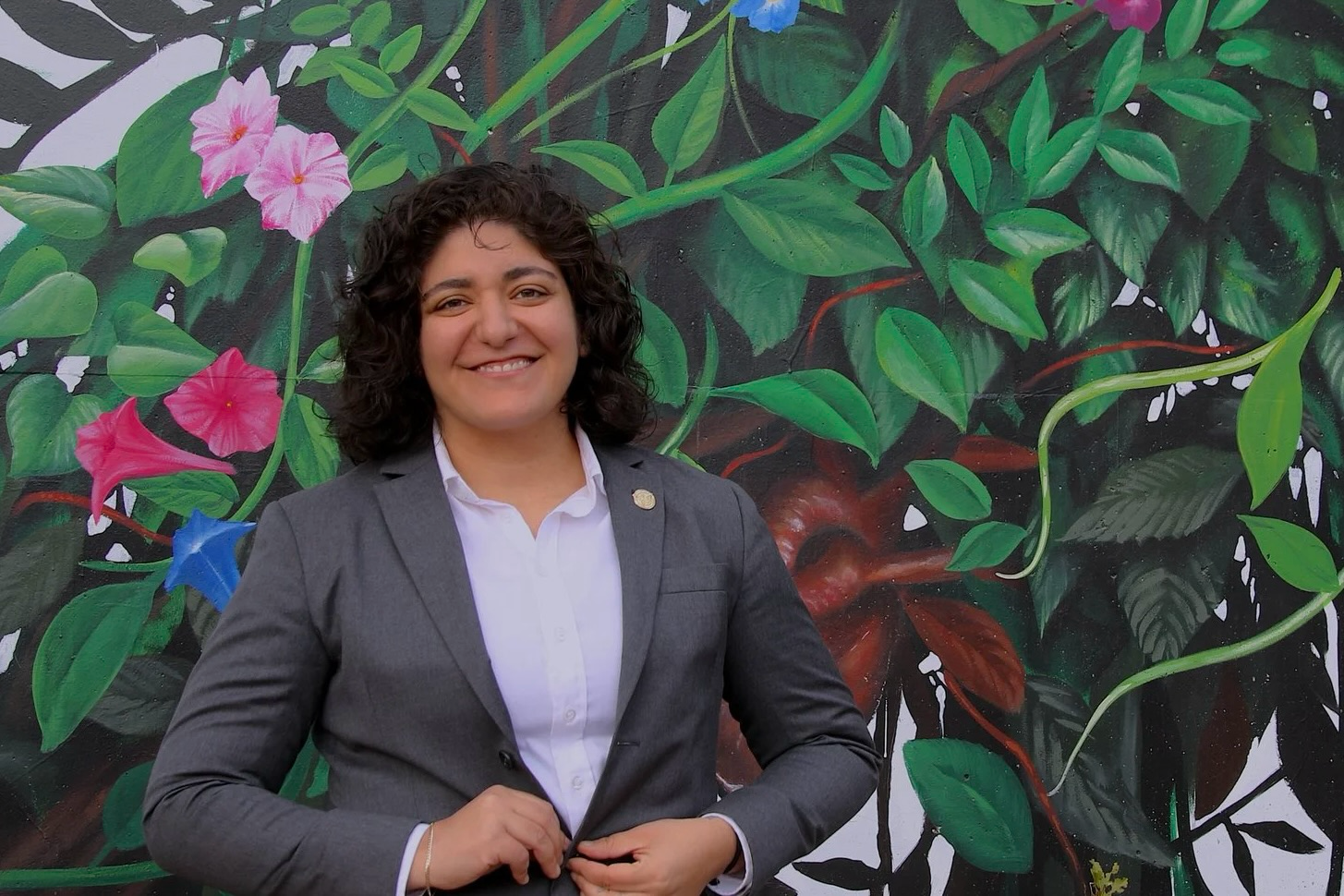 Councilmember Liliana Bahktiari standing in front of a mural of vines and flowers