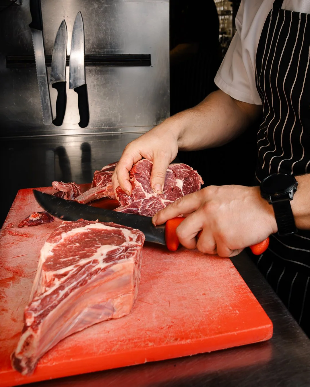 Rockwall Bar and Grill Head Chef Nick Garth carving pasture raised Tasmanian Cape Grim rib eye steak.