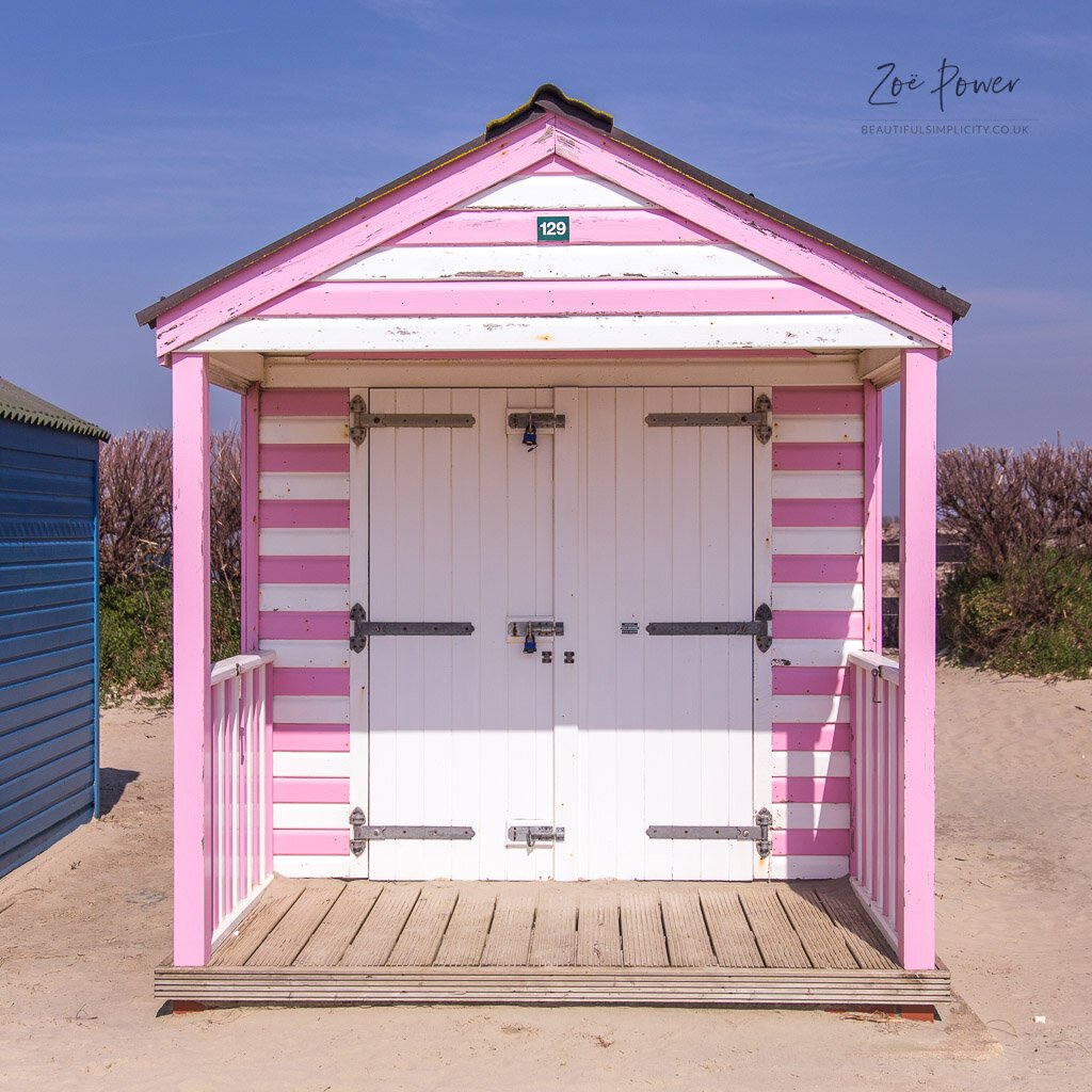 Pastel pink and white striped wooden beach hut on West Wittering