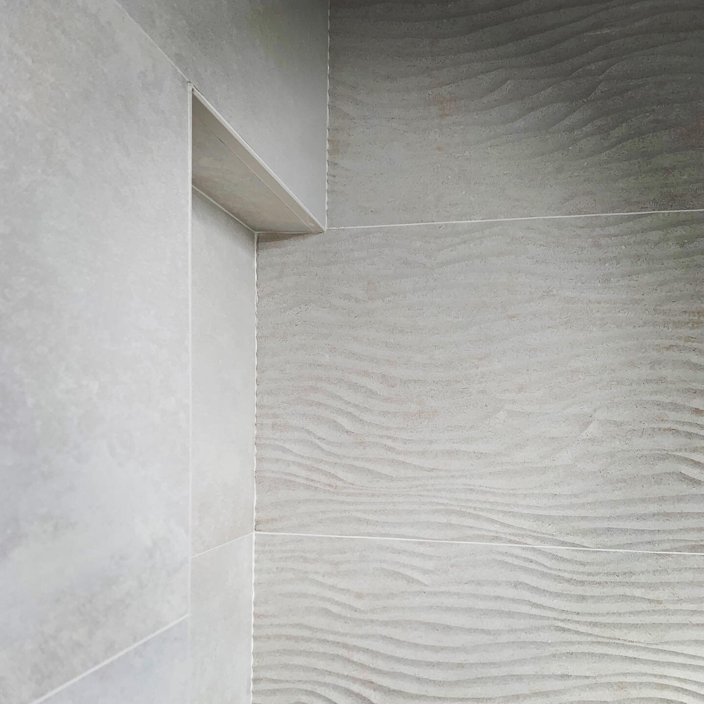 This @porcelanosa shower niche is awaiting glass shelves.  The movement on this tile is mesmerizing&mdash; making a statement without being too loud and so apropos for this coastal home.