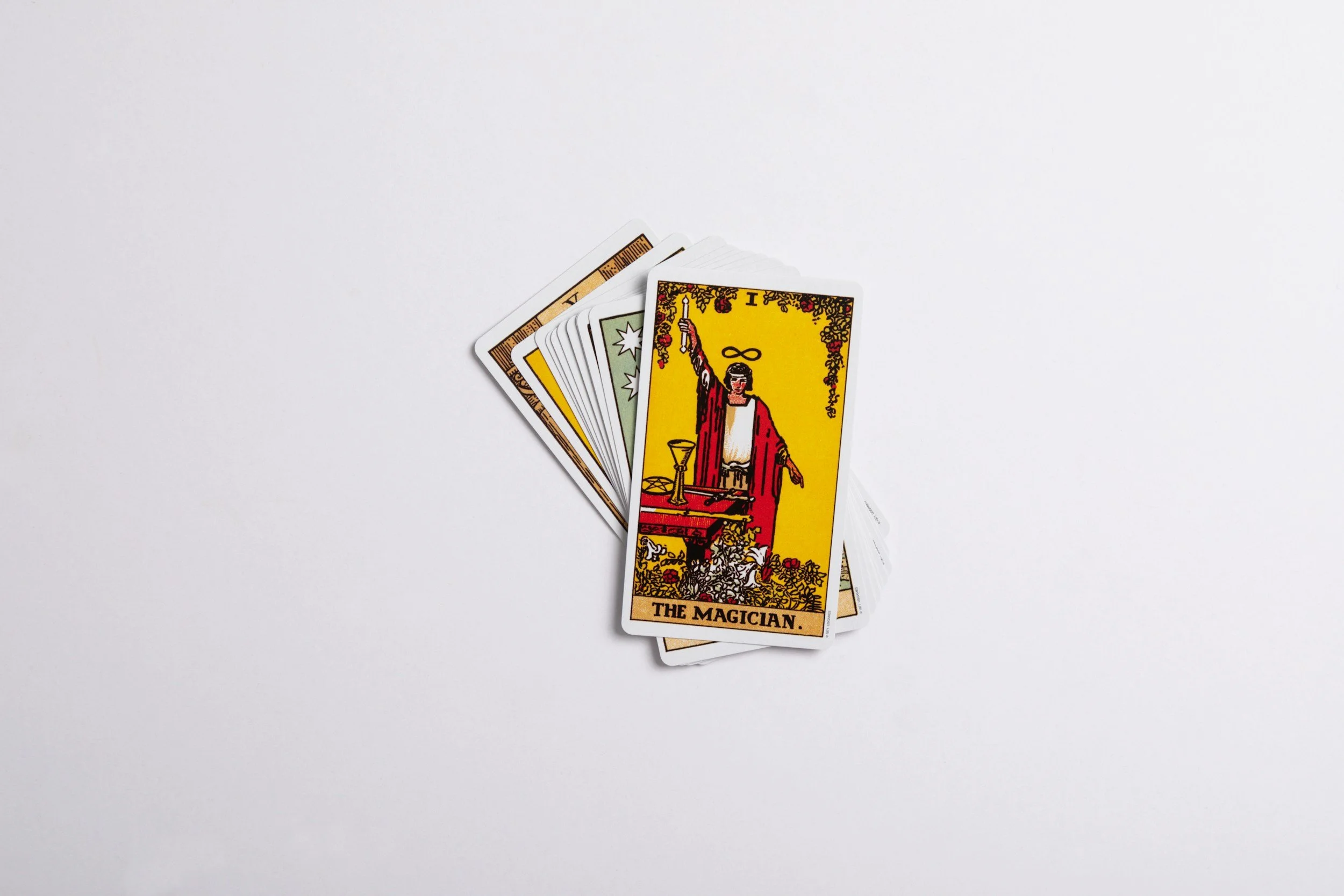 A spread of tarot cards with The Magician card on top, placed on a white surface.