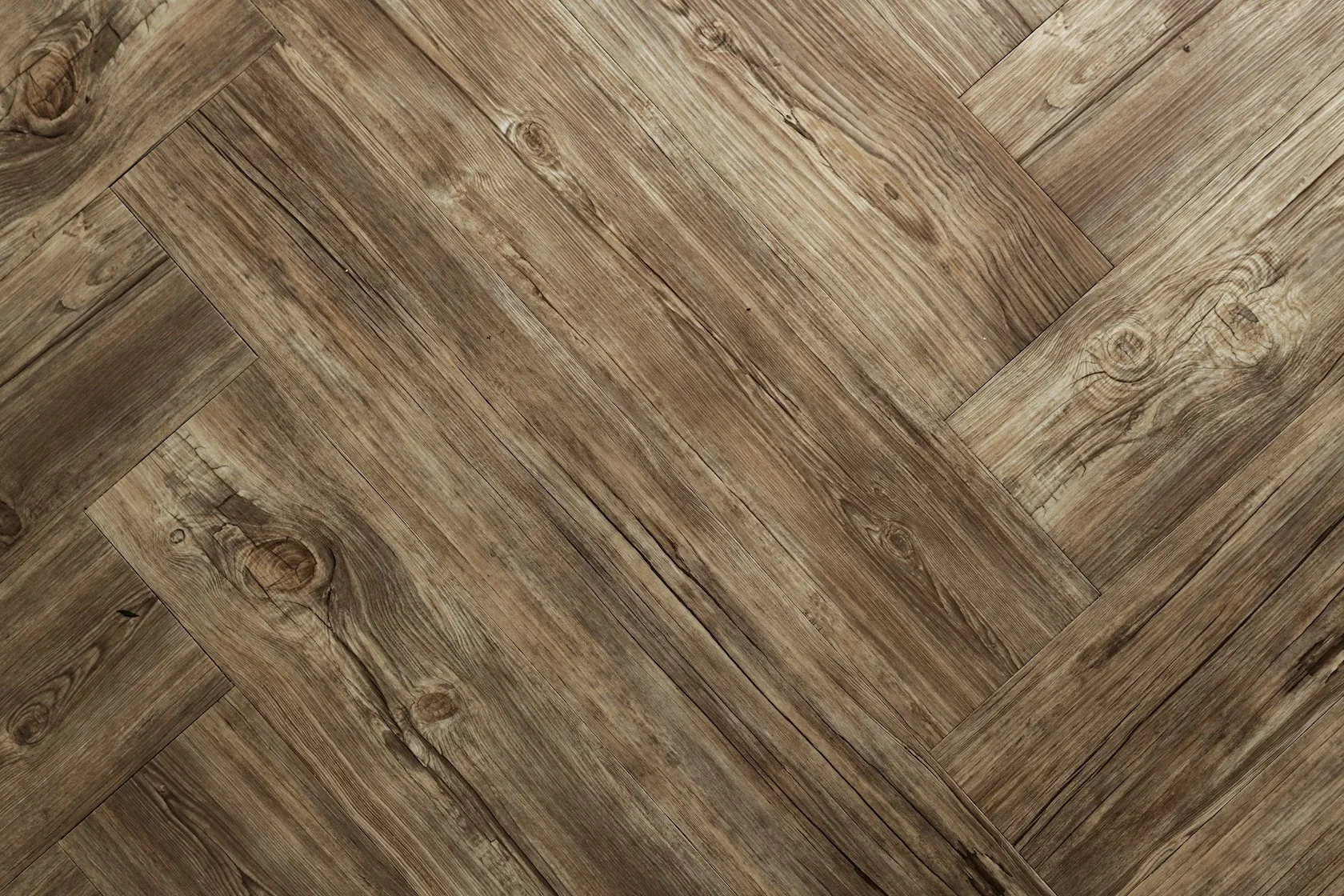 Close-up of a wooden herringbone-patterned floor with visible wood grain and knots.