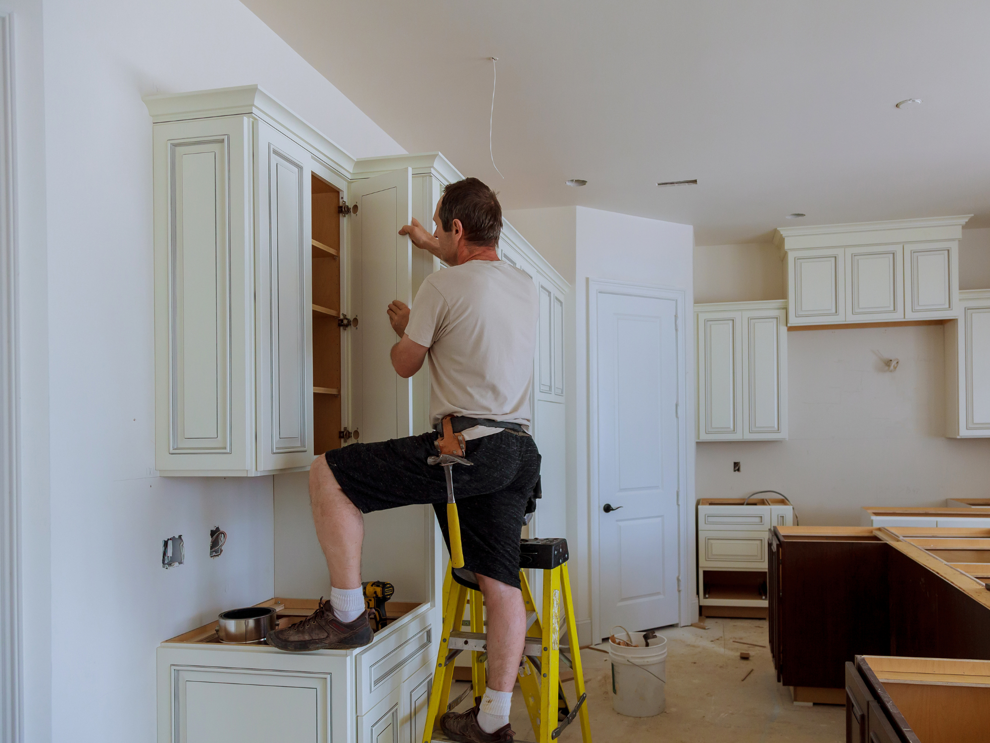 A man installing kitchen cabinets in a new home under construction.