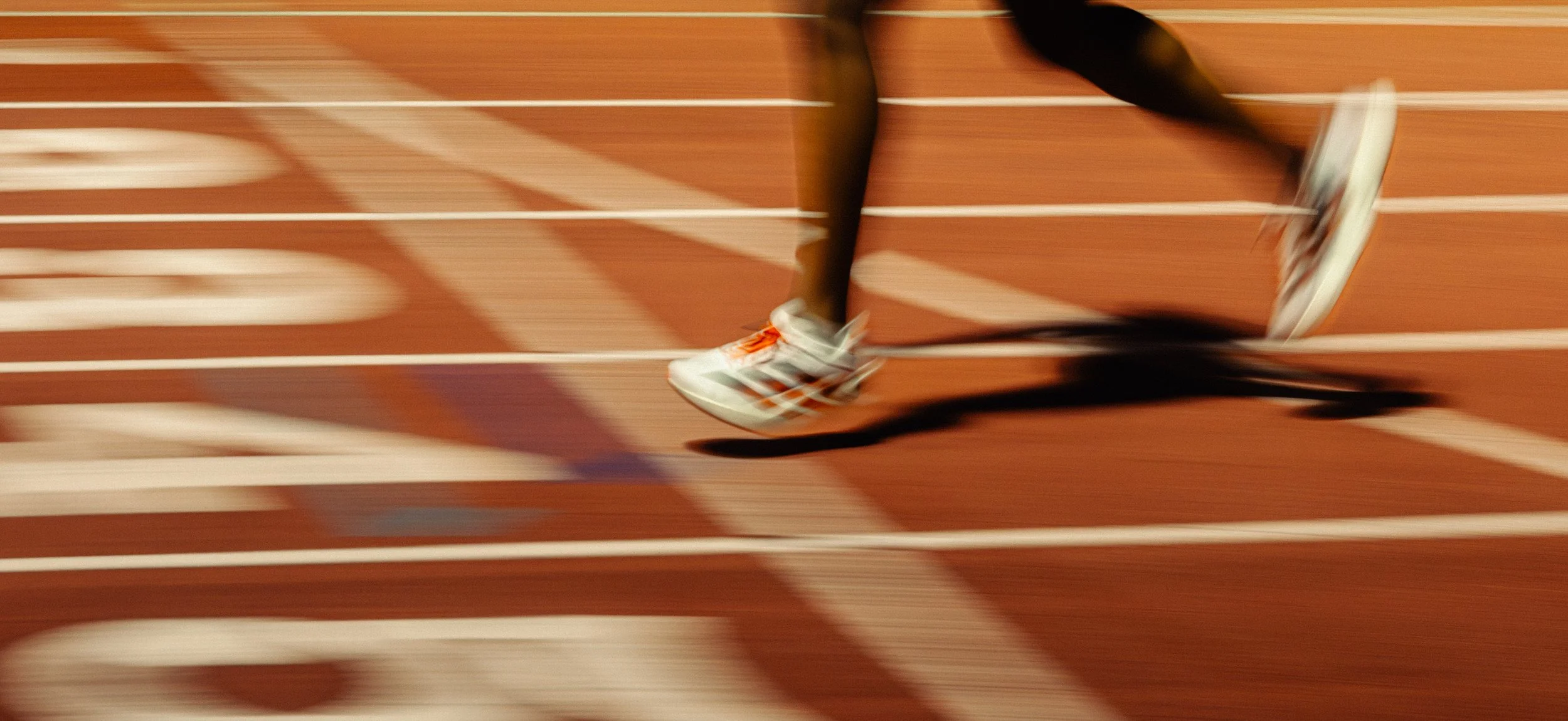 Dynamic motion blur of Adidas shoes on the track, emphasizing rhythm, speed, and the kinetic energy behind every stride.