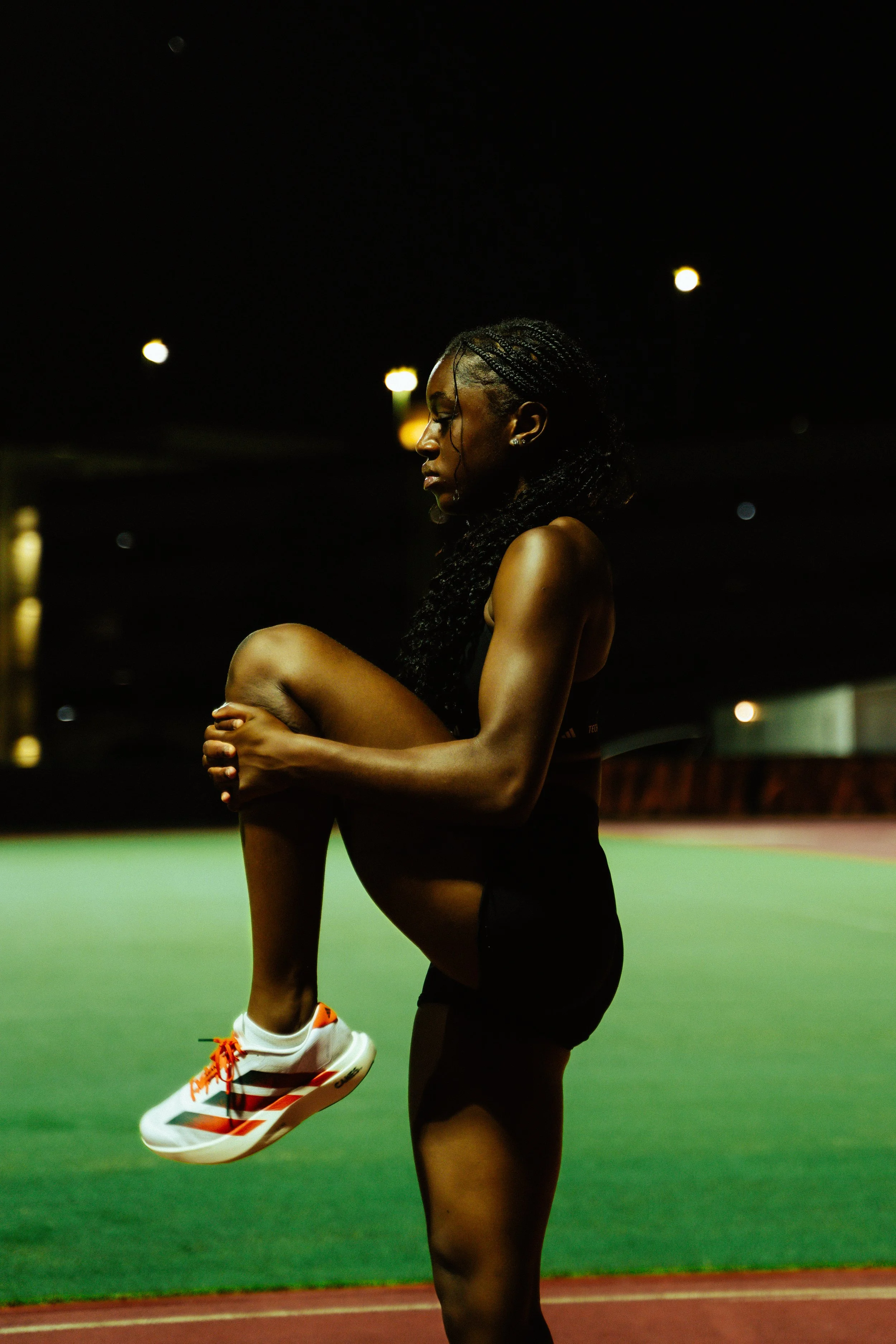 Low-light portrait of athlete in Adidas training gear under stadium lights, merging strength and serenity in an editorial moment.