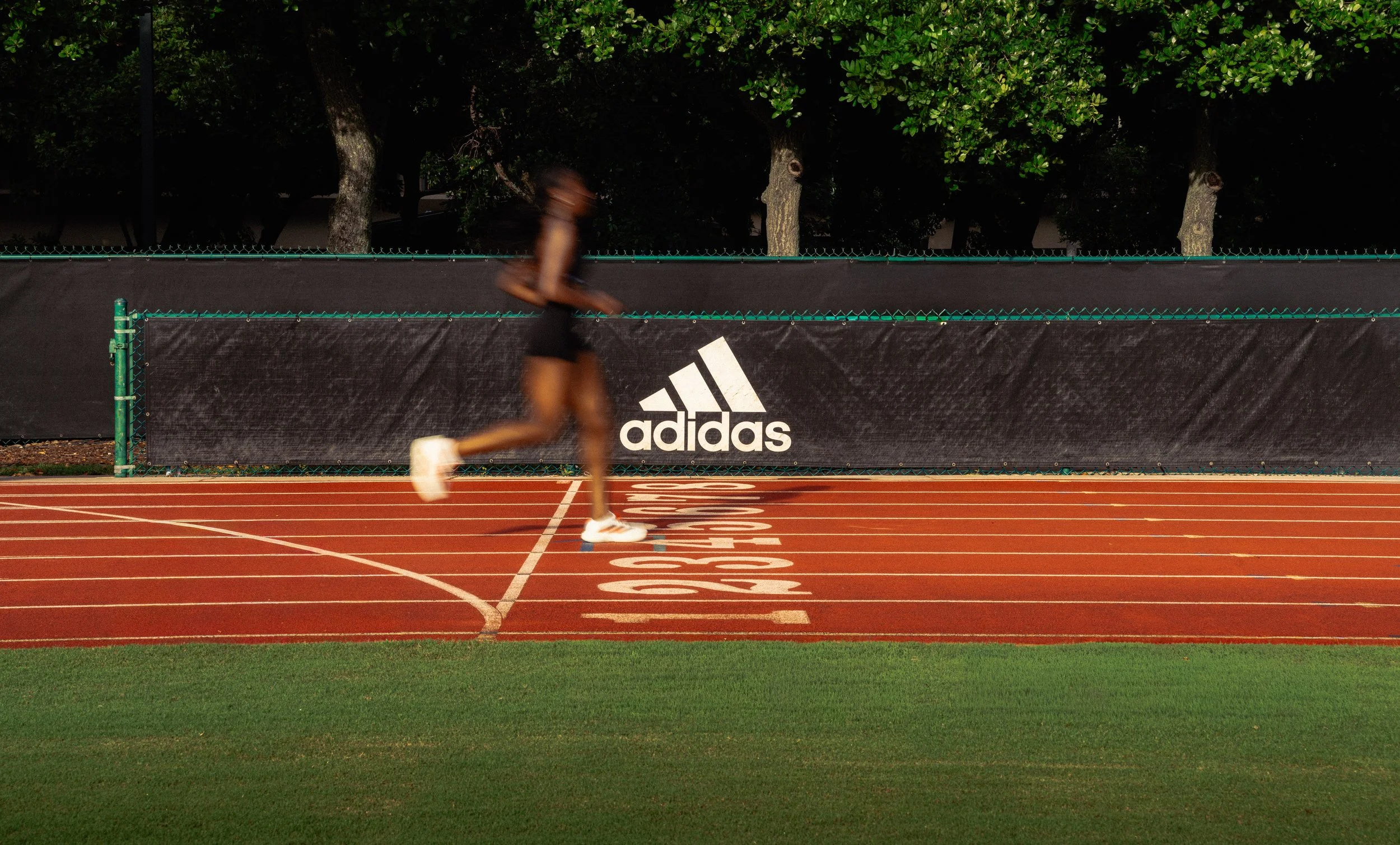 Adidas x University of Miami athlete sprinting down the track, captured at golden hour to highlight power, movement, and focus. Photographed by Stephen Luttinger in South Florida.
