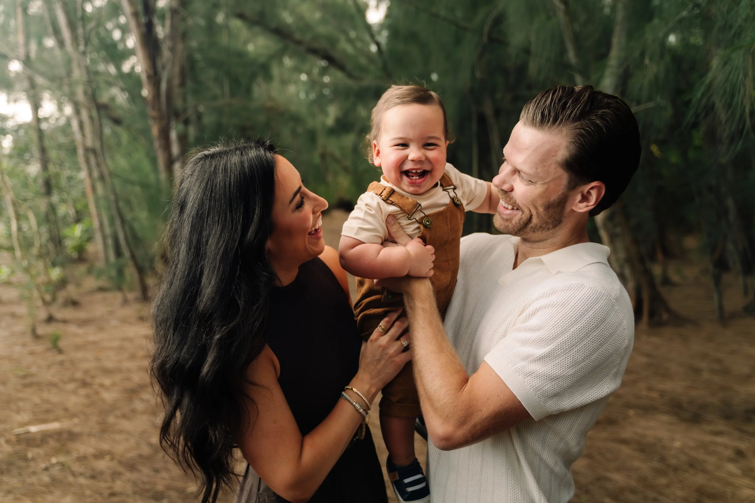 Candid family moment with parents lifting their toddler and smiling at Markham Park. Natural, joyful family photography by Stephen Luttinger Photography.