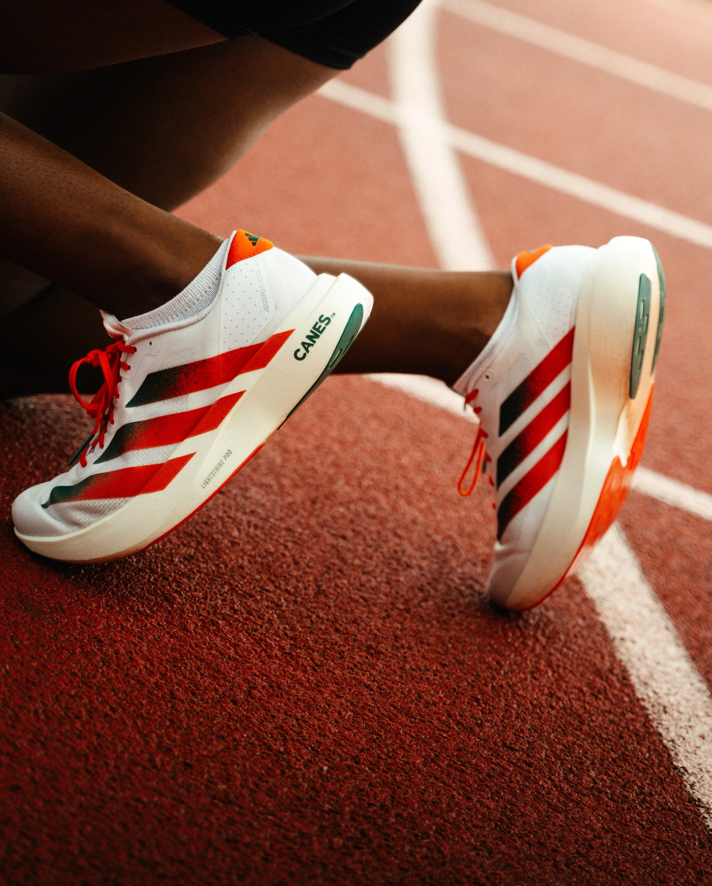 Athlete tying Adidas sneakers before a sprint, photographed at the University of Miami by Stephen Luttinger Photography — representing focus, ritual, and readiness.