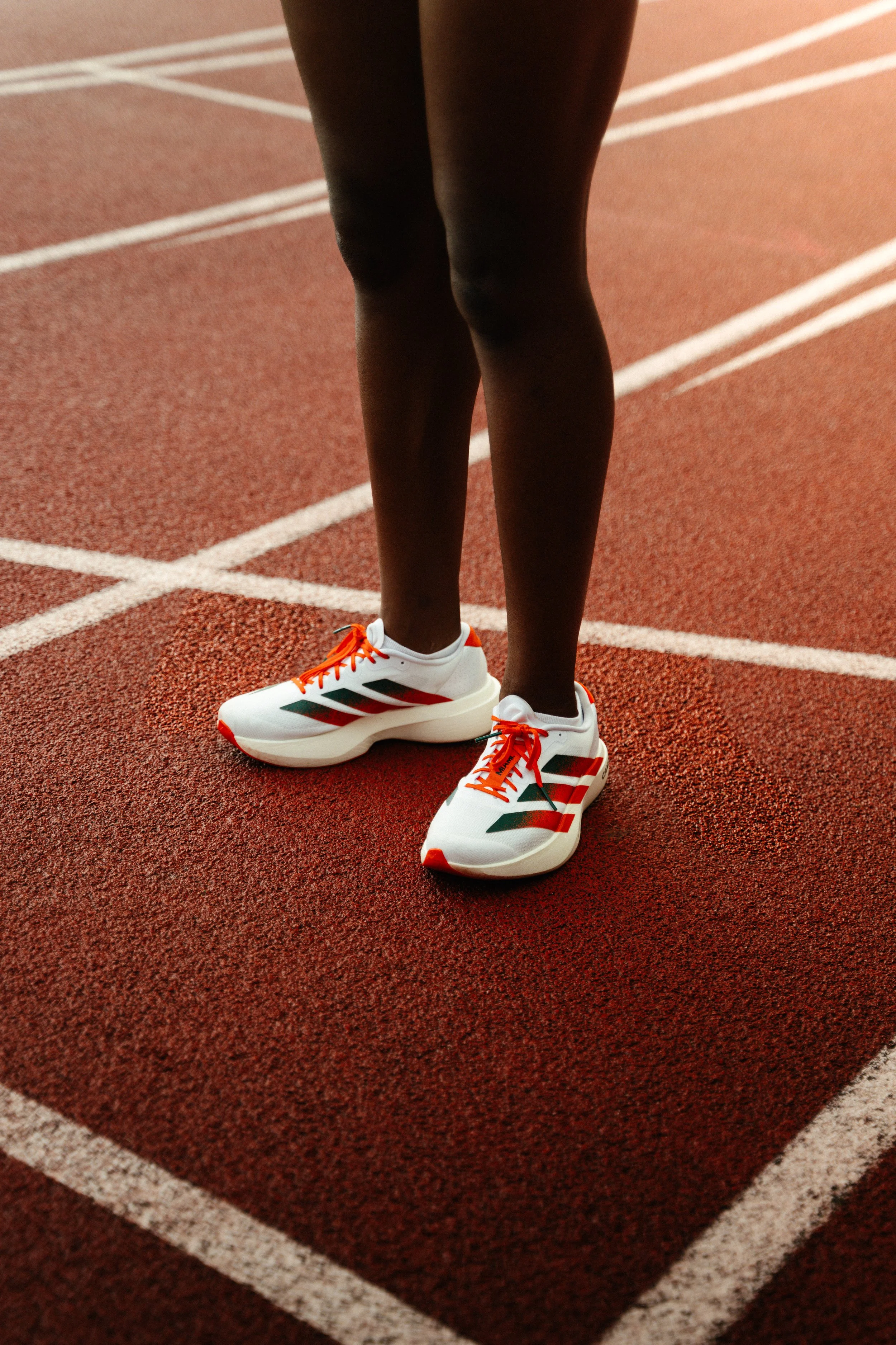 Adidas running shoes photographed under soft evening light on the track, balancing performance design with lifestyle visuals.