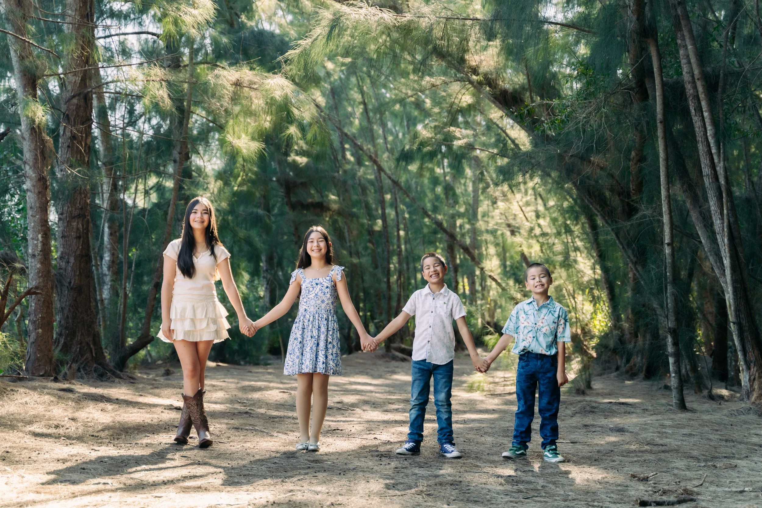 Candid siblings portrait holding hands on a sunlit forest path at Markham Park. Natural family photography by Stephen Luttinger Photography.