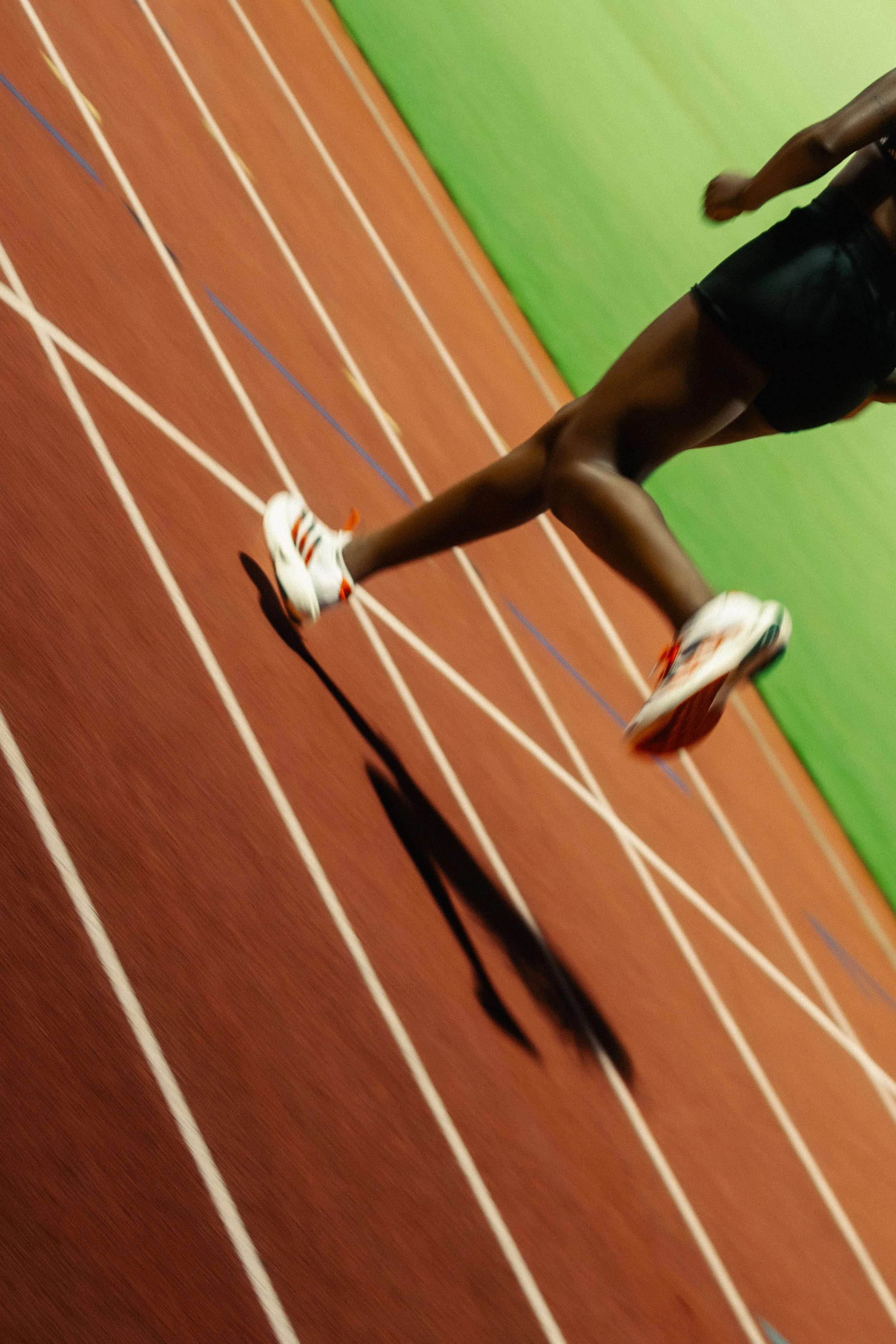 Low-angle track shot of Adidas runner mid-stride, expressing the speed, balance, and athleticism behind Adidas’ performance ethos.
