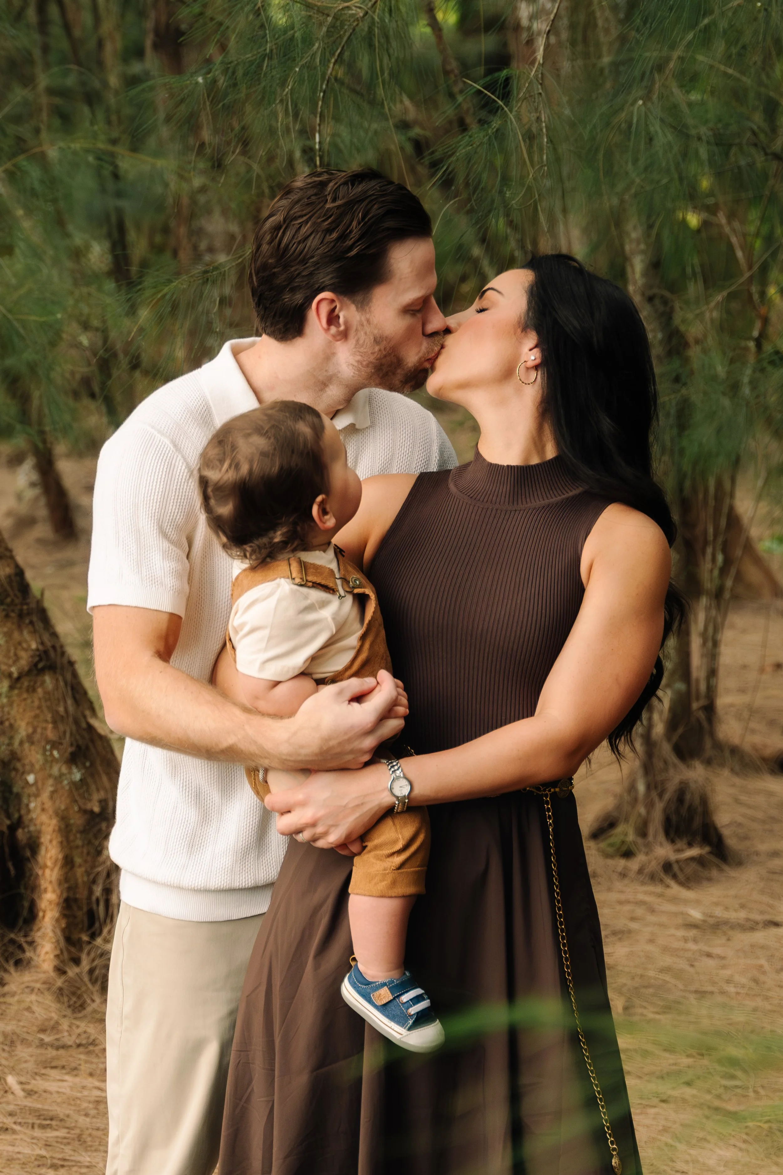 Warm, intimate family portrait of parents holding their toddler on a shaded trail at Markham Park. Captured by Stephen Luttinger Photography.