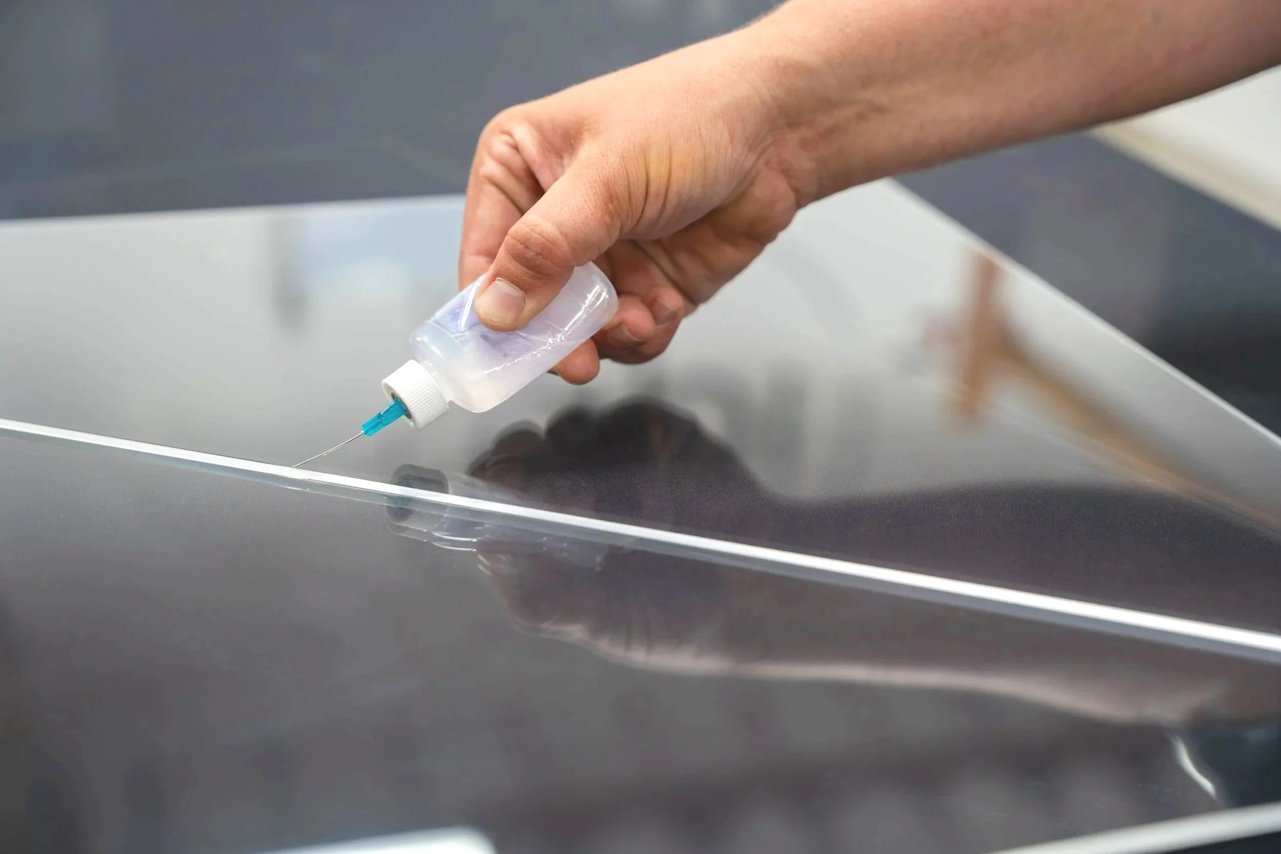 Hand-applied acrylic bonding with controlled adhesive flow and seam alignment for clear display assemblies.