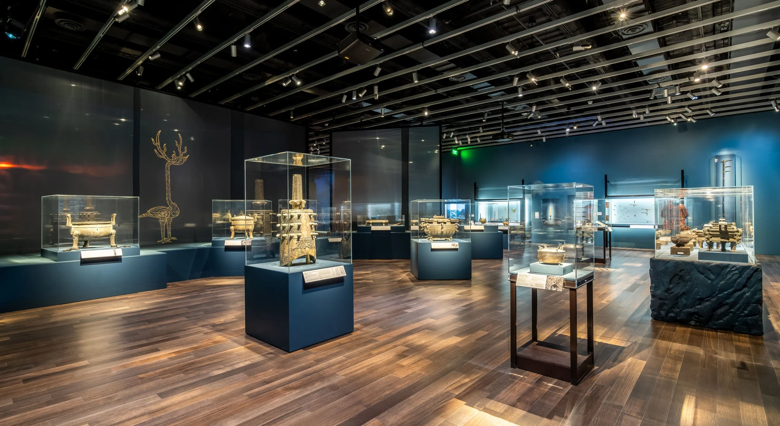 Part of a large museum exhibit of Chinese artifacts showing multiple acrylic display cases with painted plinths.