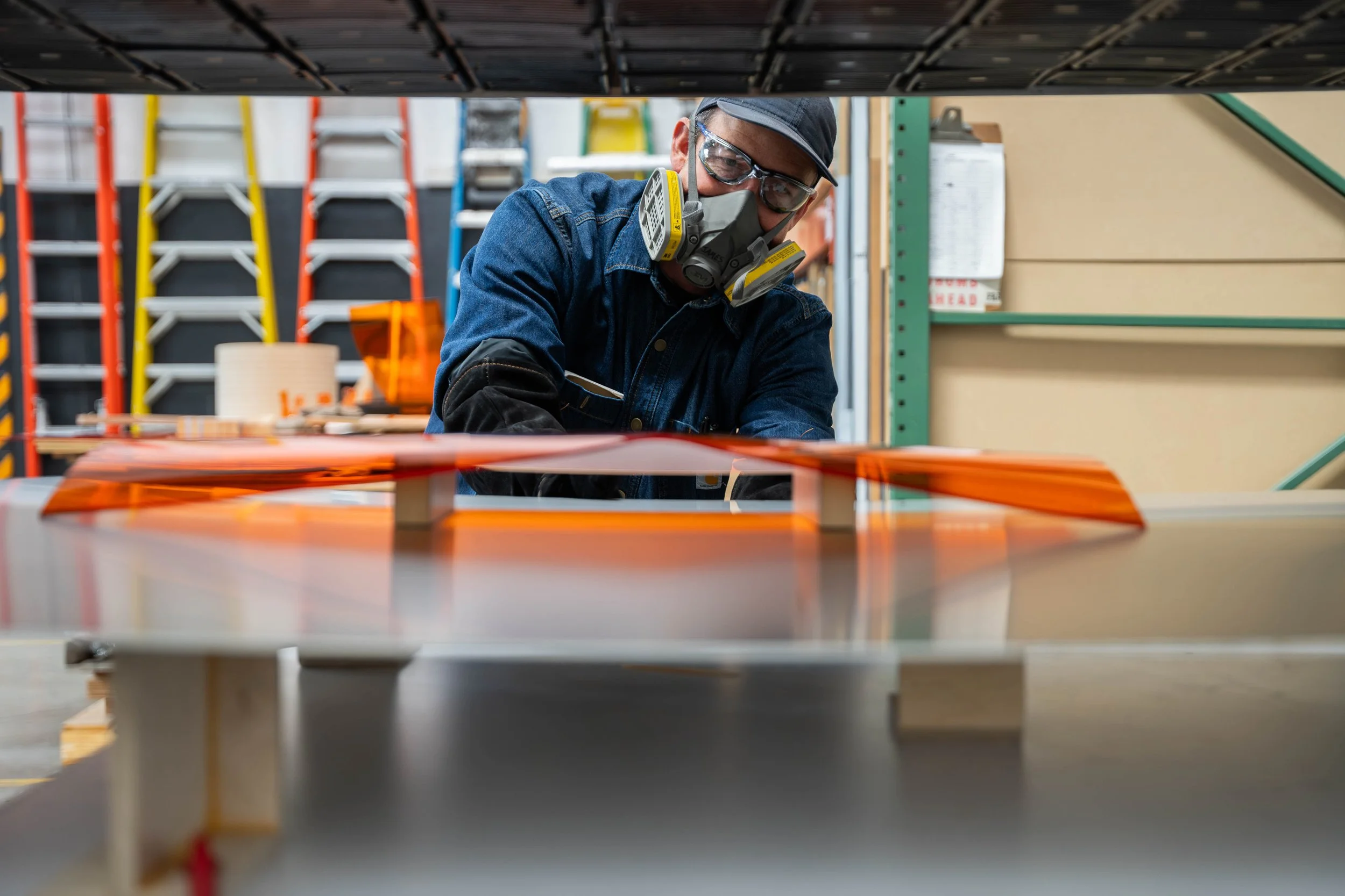 Architectural Plastics, Inc. fabricator checking the temperature of a transparent orange acrylic panel during thermoforming.