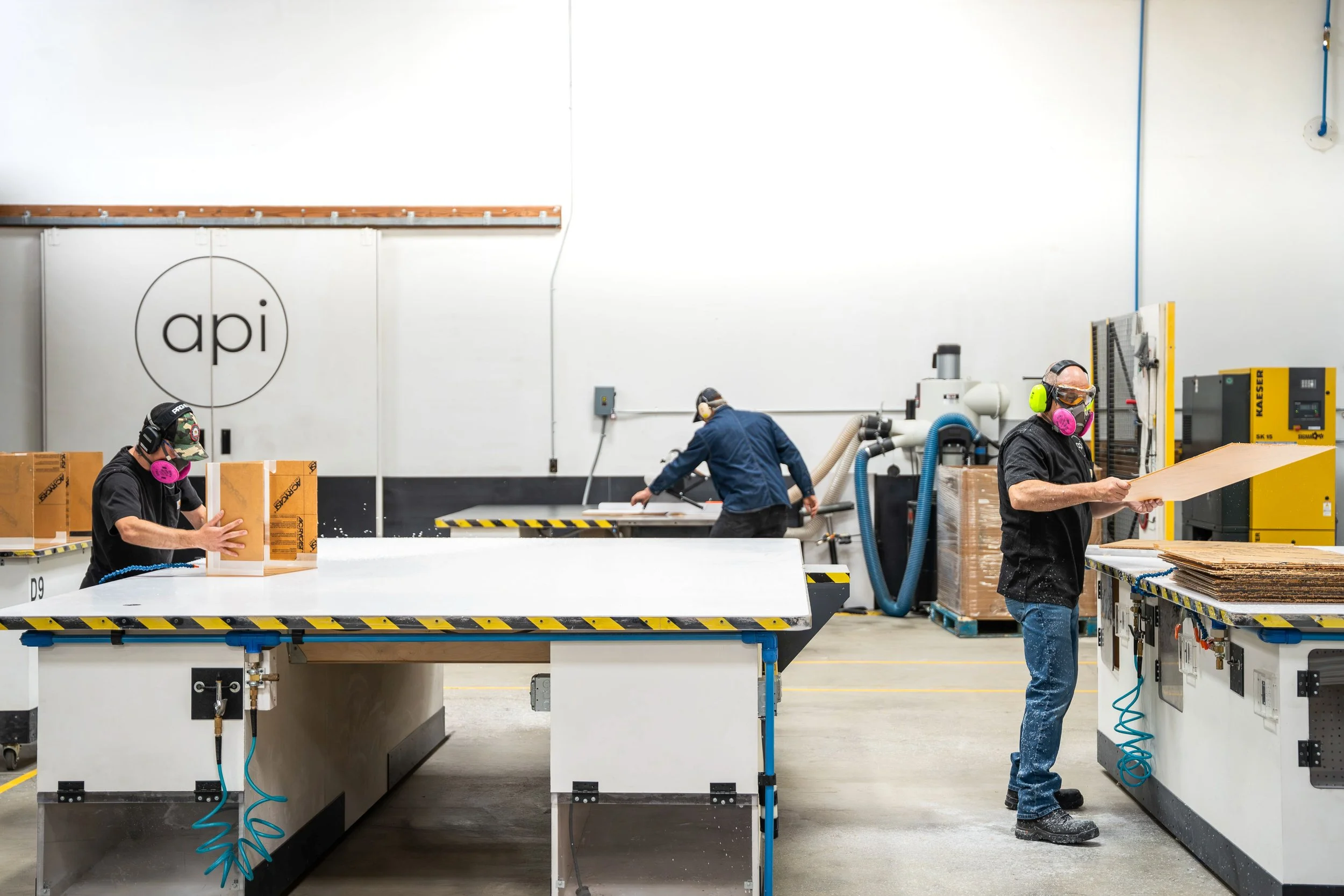 Three plastic fabricators in a shop processing panels and glued assemblies.