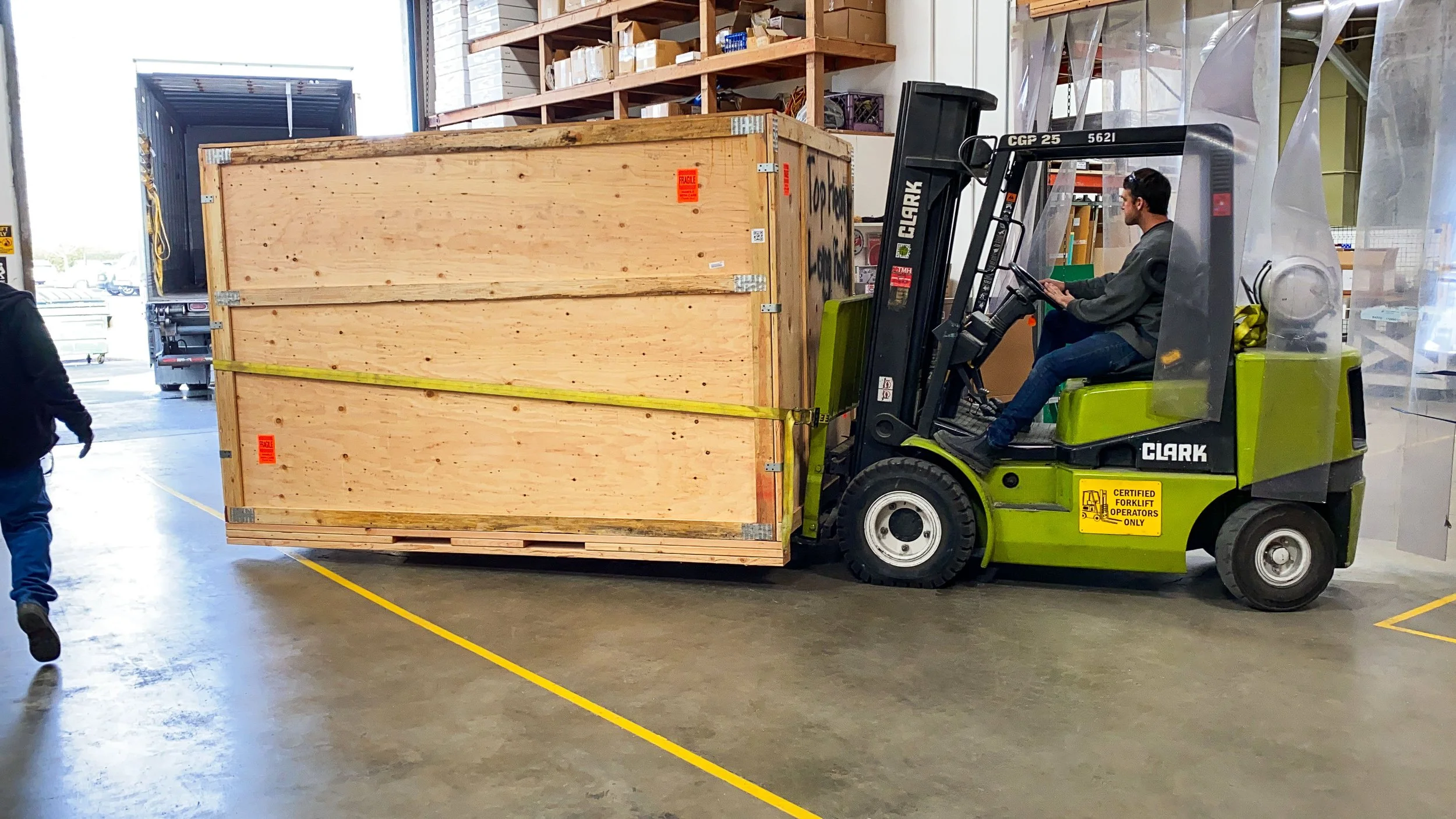 Forklift transporting a large wooden shipping crate built to protect finished acrylic work in transit.