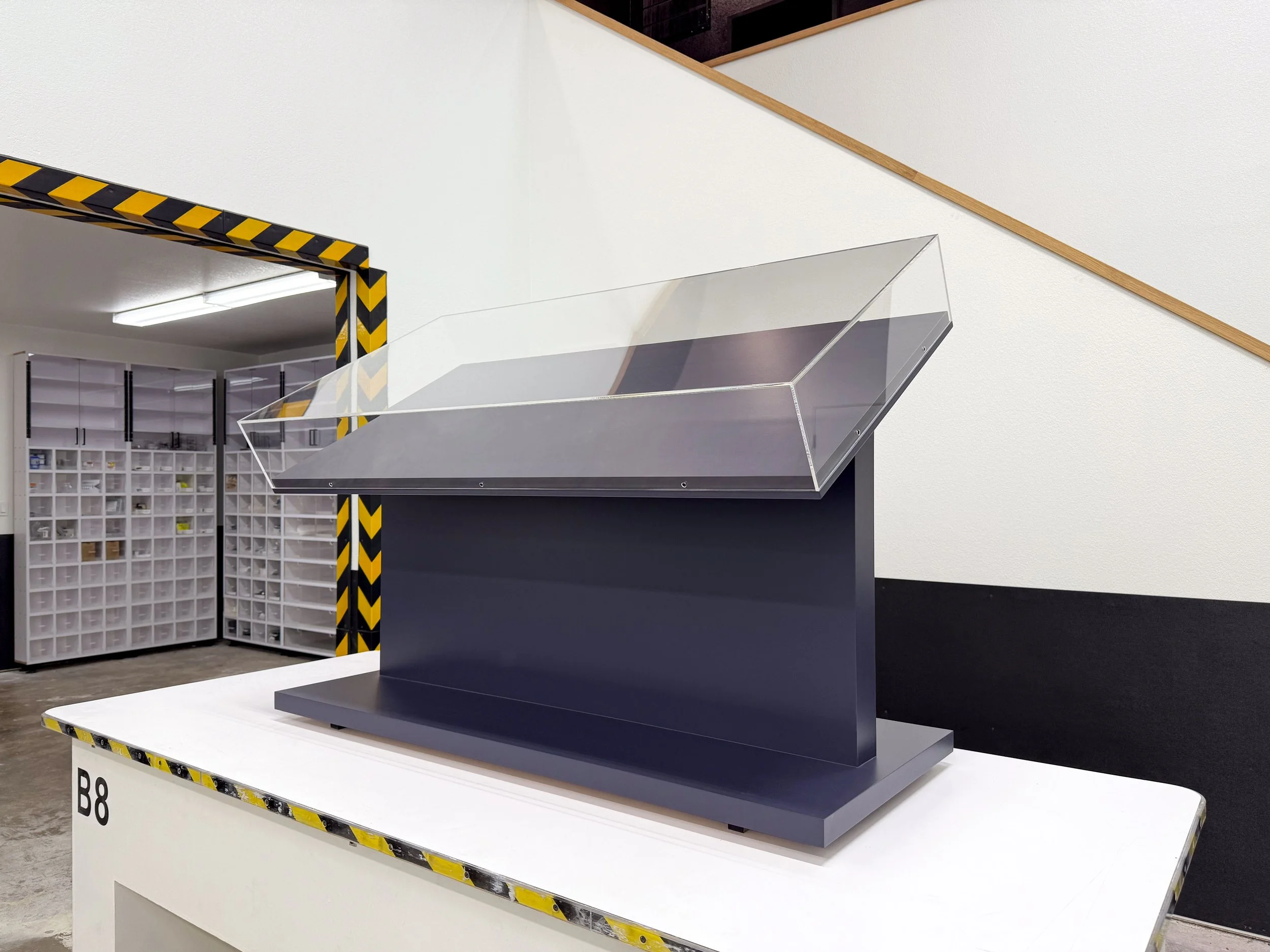 Tru Vue Optium Museum Acrylic vitrine on top of an angled plinth painted blue.  
