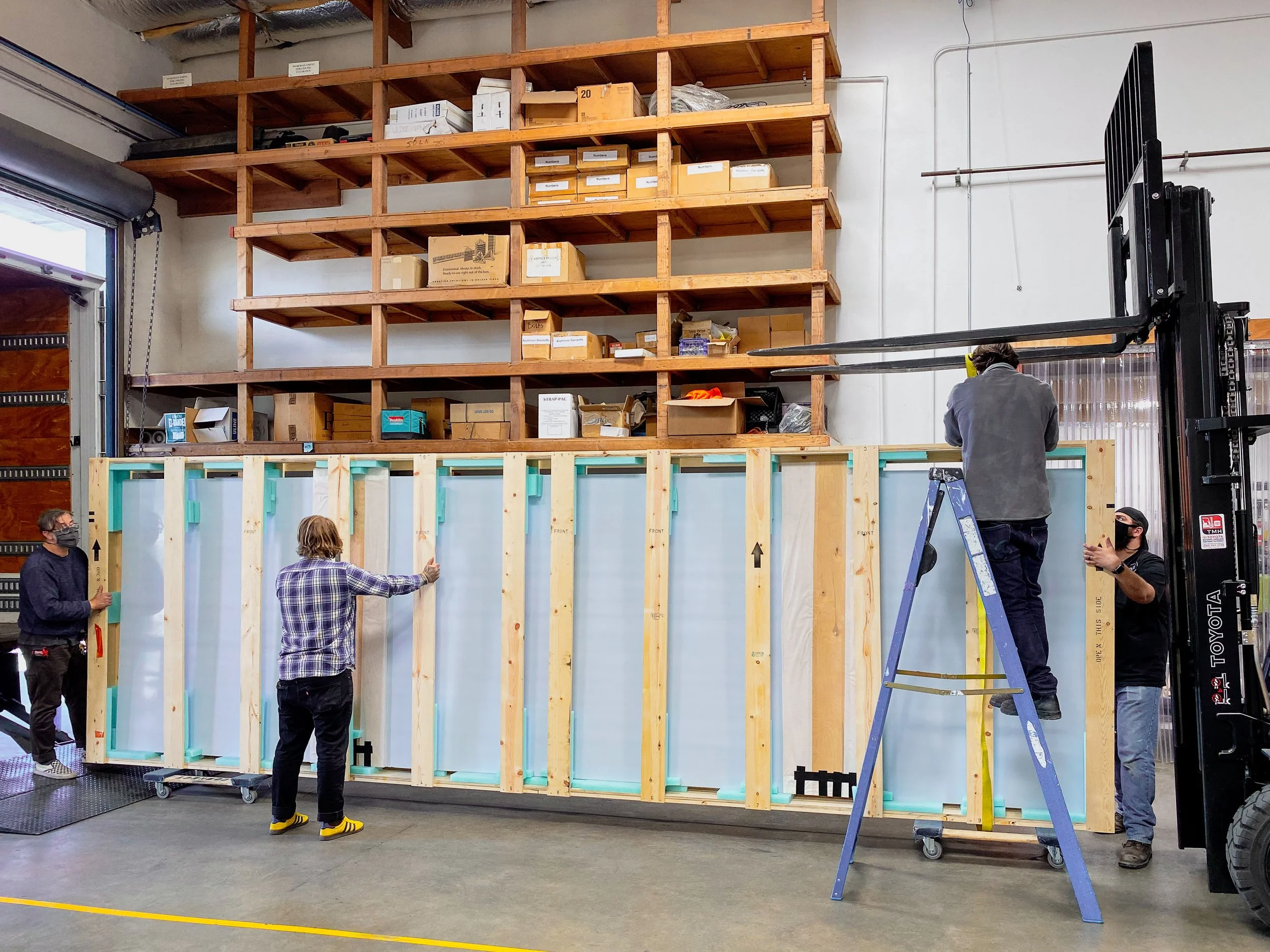 Fabricators rigging up a double seamed Tru Vue Optium panel in a crate to be loaded onto a box truck.